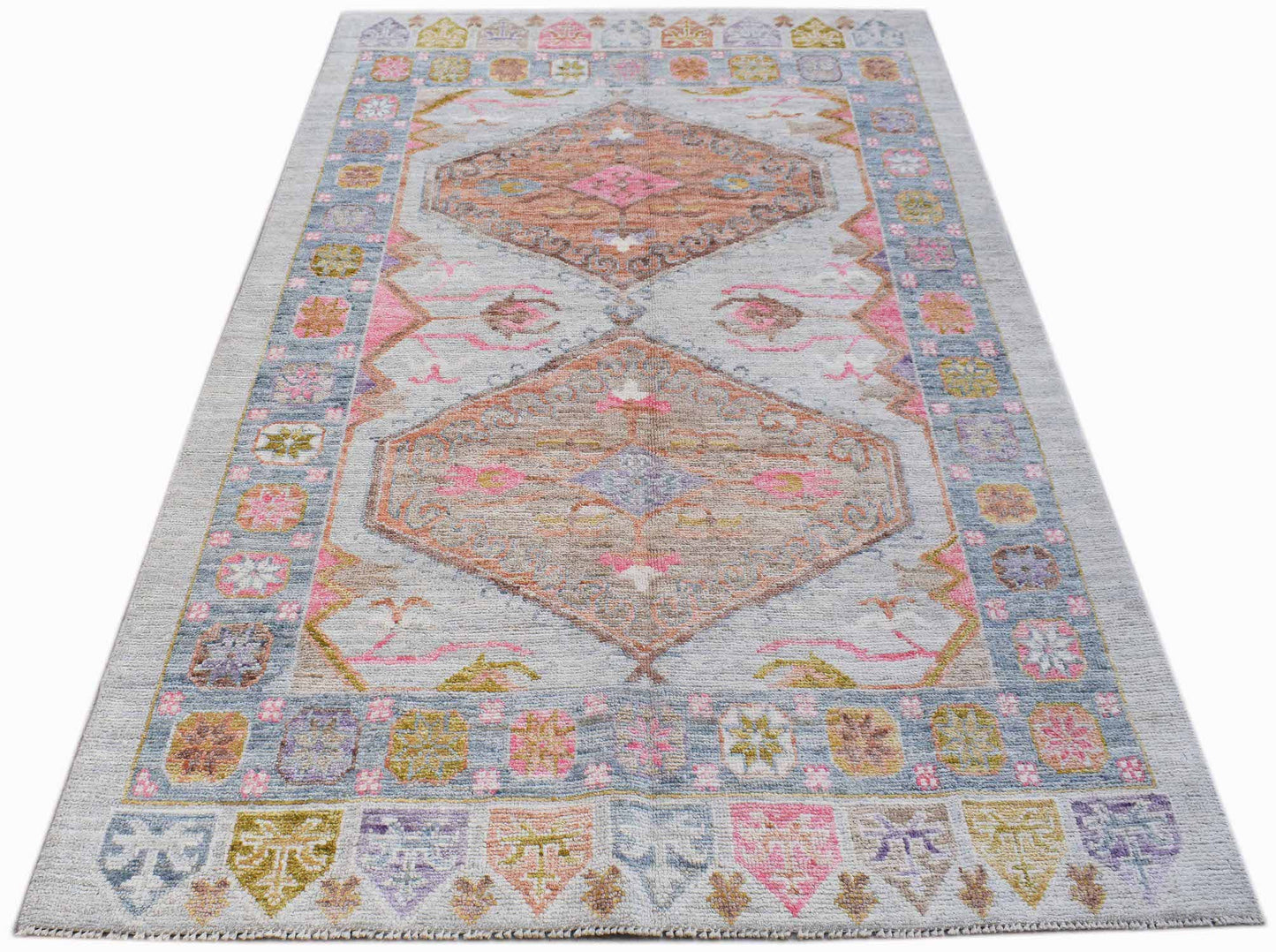 A handwoven transitional Oushak rug featuring a light grey background with pink and tan medallions.