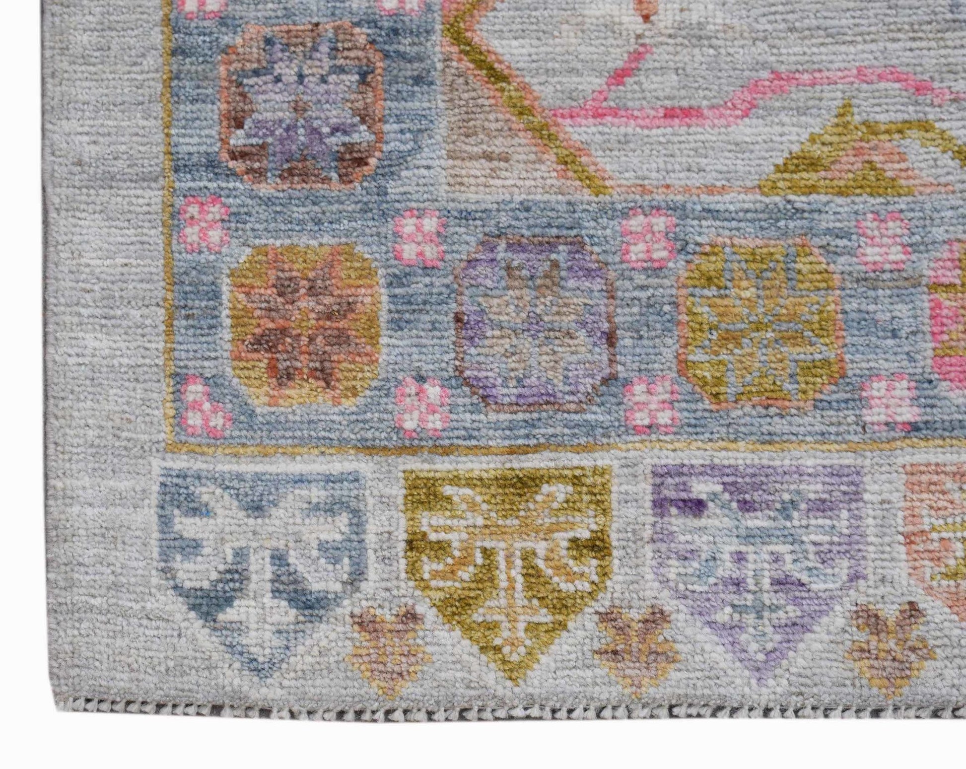 A handwoven transitional Oushak rug featuring a geometric floral pattern in soft pastel tones.