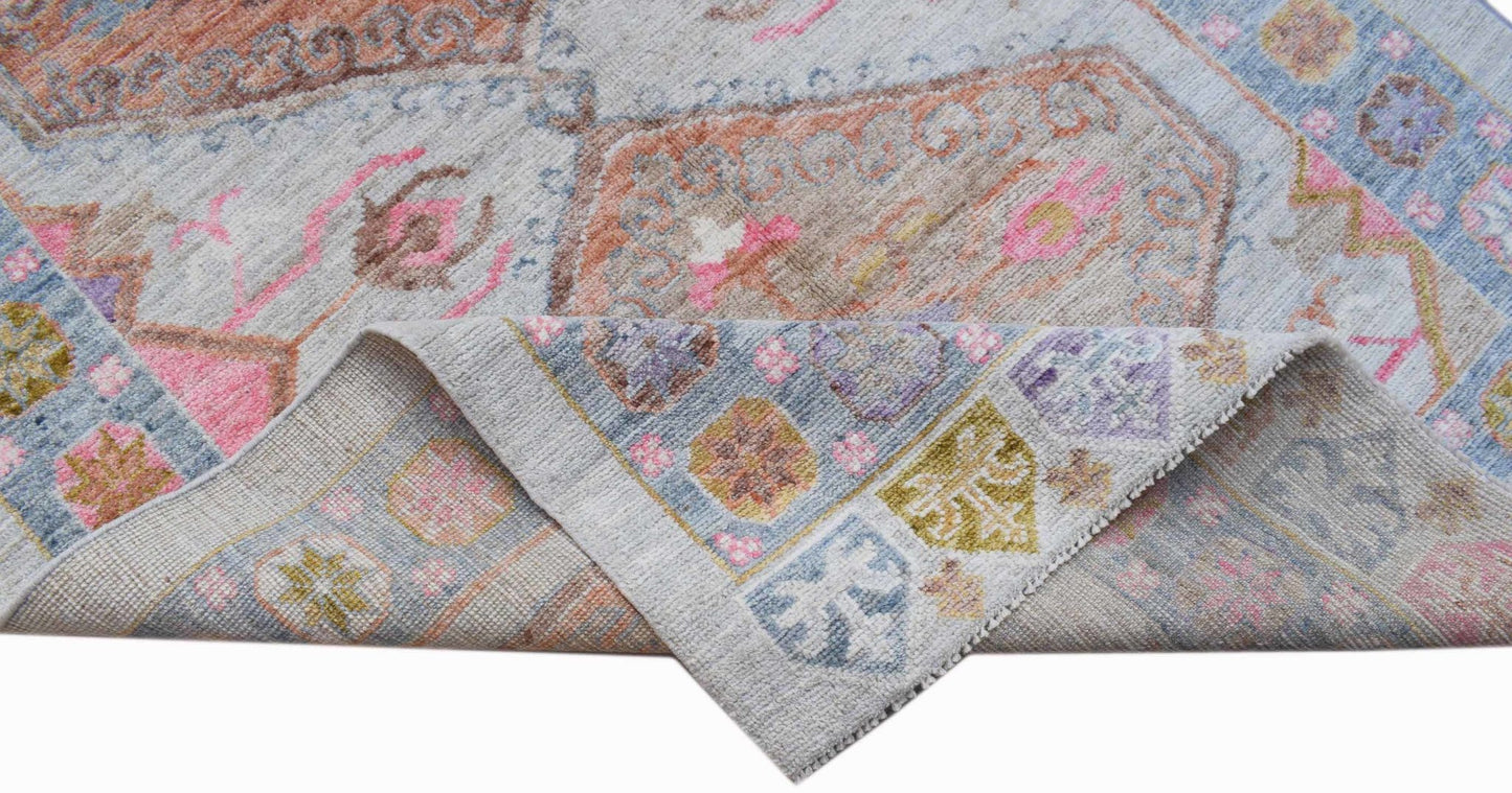 A handwoven transitional Oushak rug featuring a floral pattern in soft blue, pink, and tan tones.