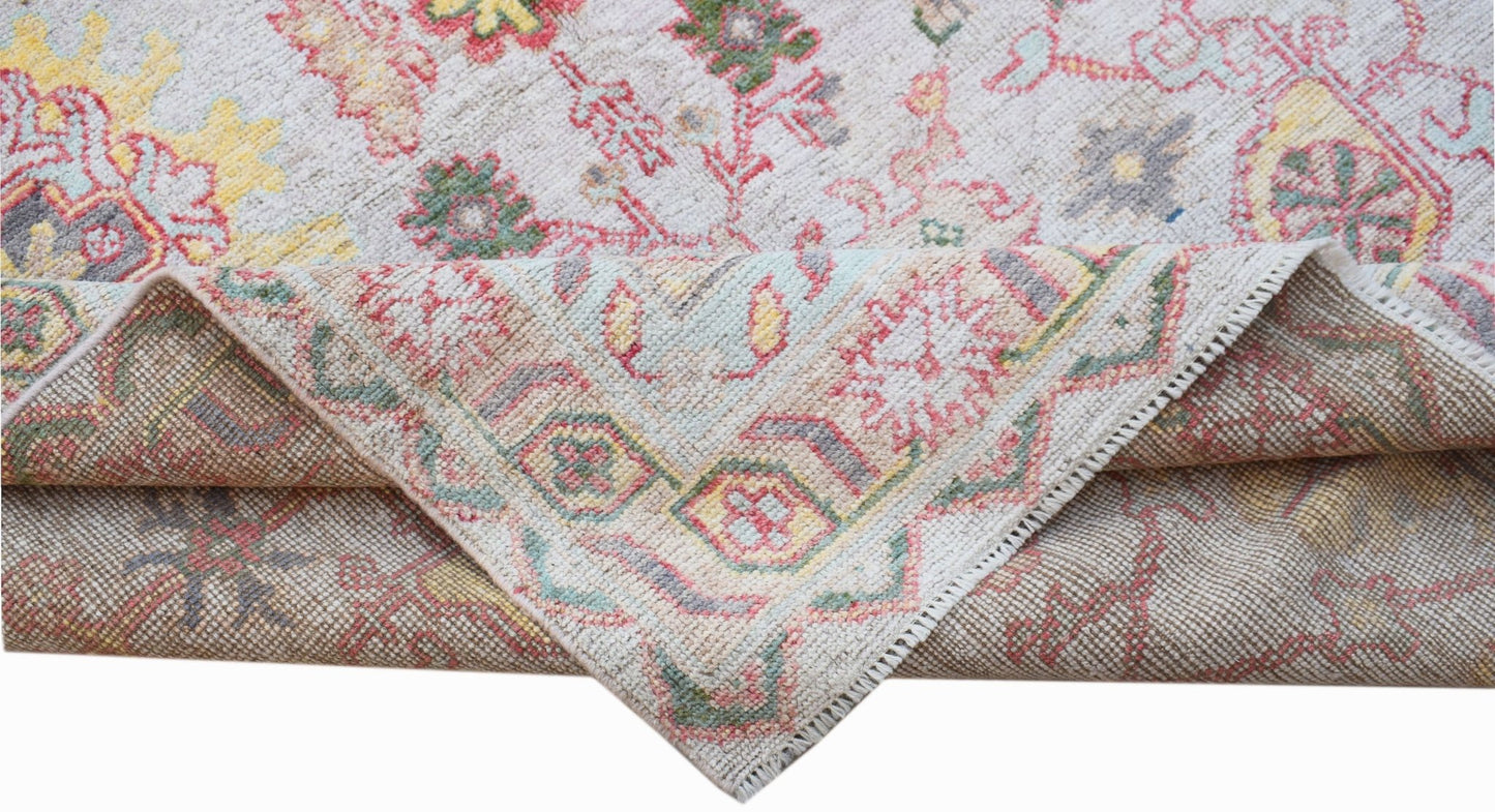 A handwoven transitional Oushak rug featuring a floral pattern in soft pastel tones.