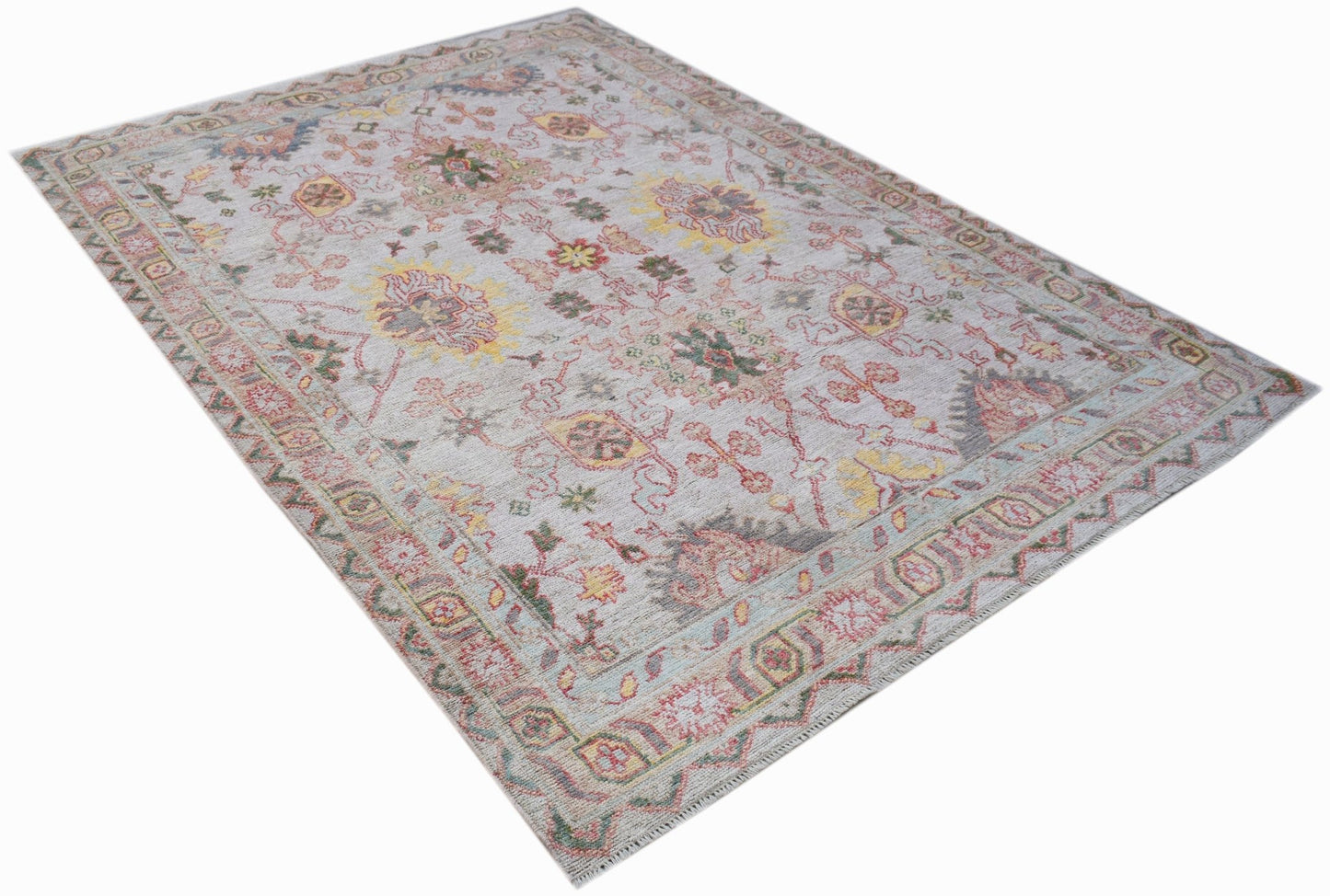 A handwoven transitional Oushak rug featuring a floral pattern in soft, muted colors.