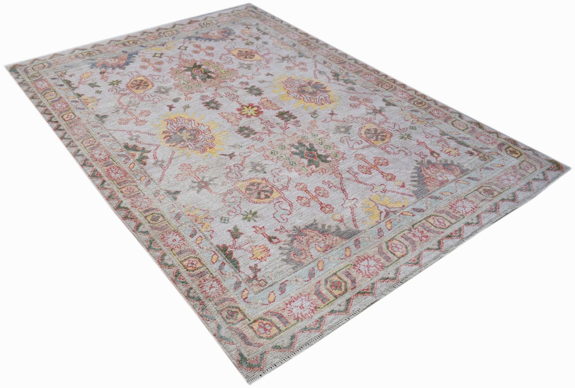 A handwoven transitional Oushak rug featuring a floral pattern in soft, muted colors.