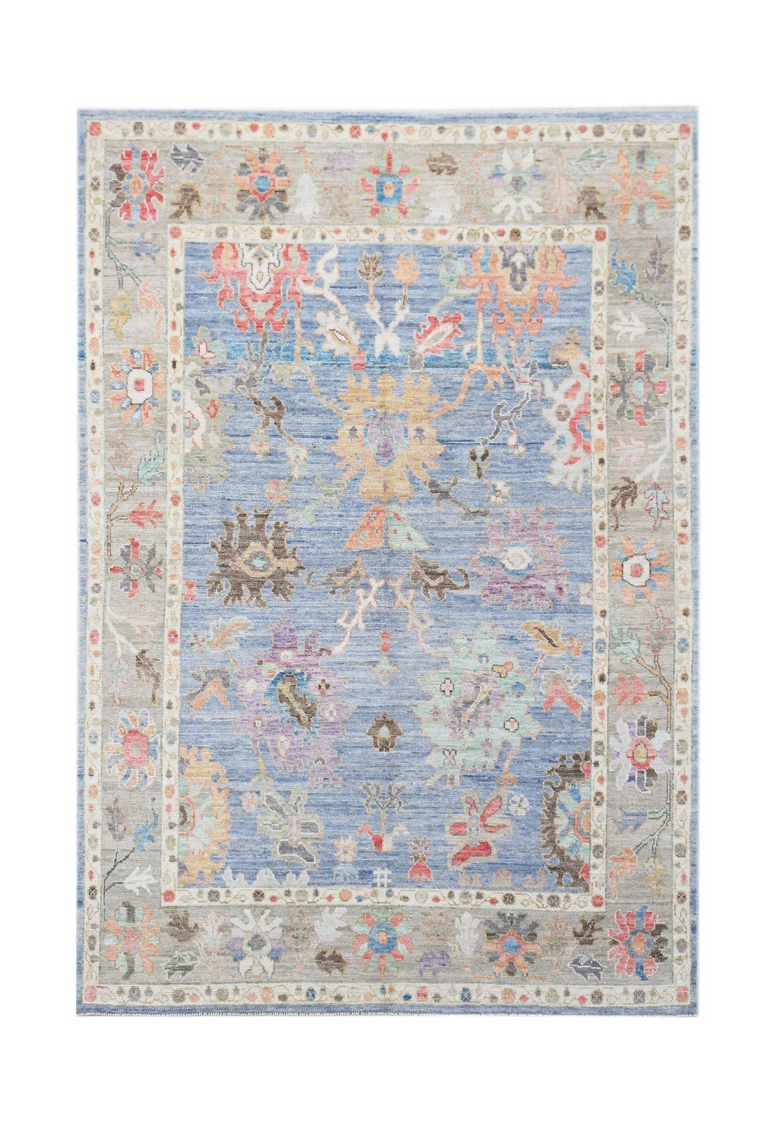 A handwoven transitional Oushak rug featuring a floral pattern in blue and neutral tones.
