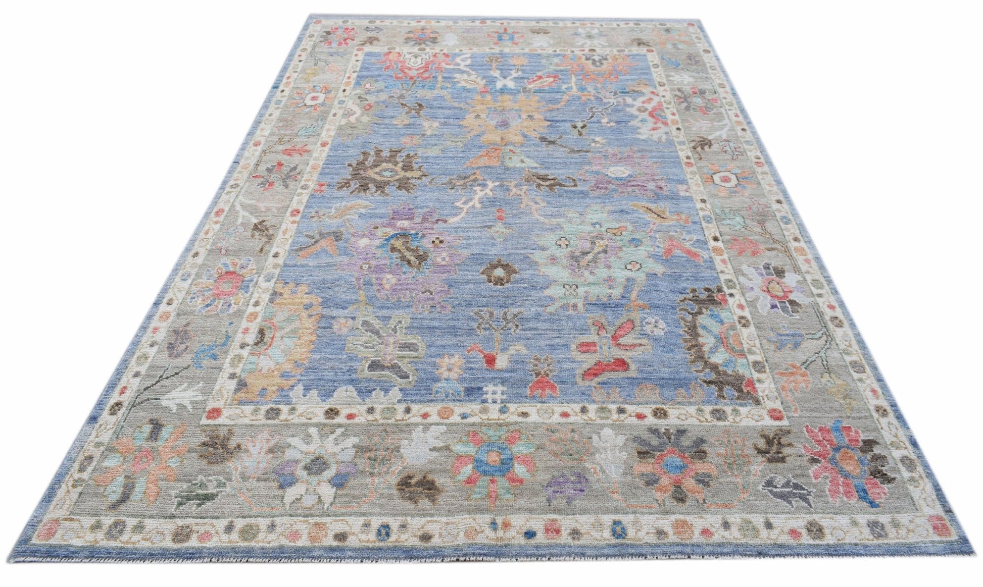 A handwoven transitional Oushak rug featuring a floral pattern in blue and multi-colored tones.