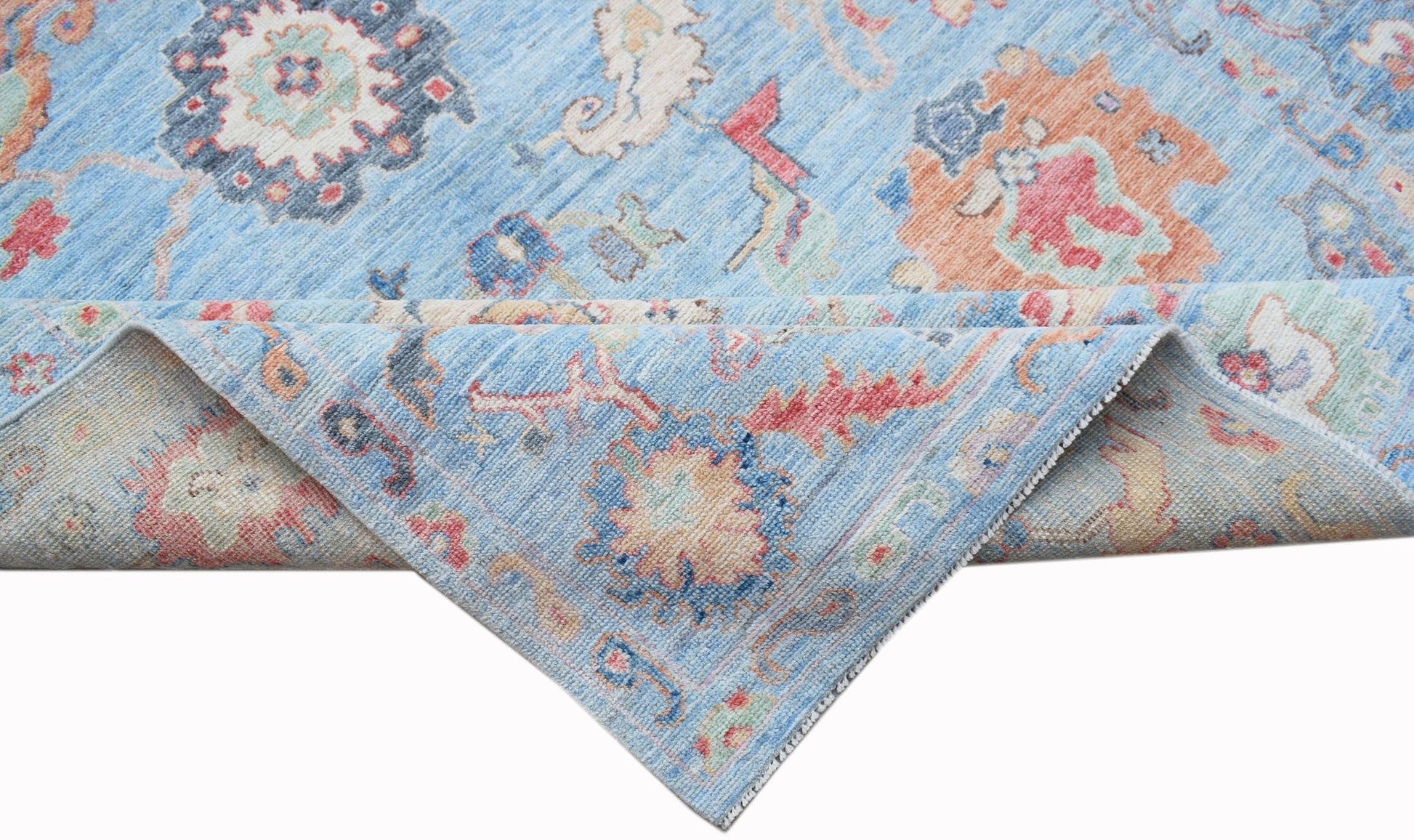A handwoven transitional Oushak rug featuring a floral pattern in blue, orange, and cream tones.