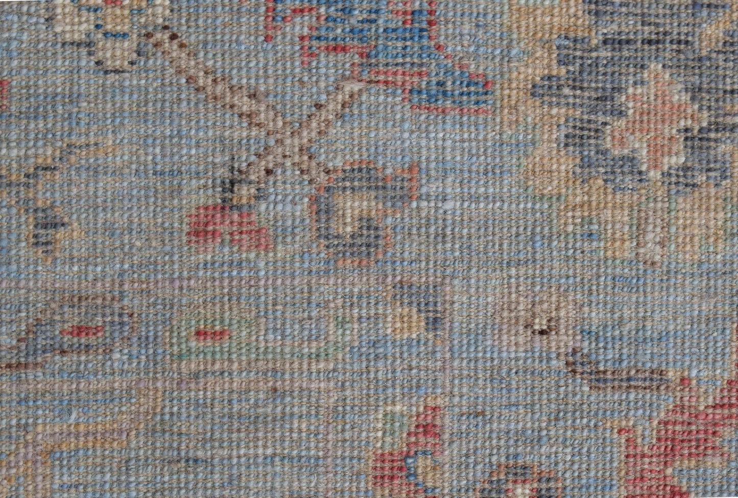 A handwoven transitional Oushak rug featuring a floral pattern in muted blue and tan tones.
