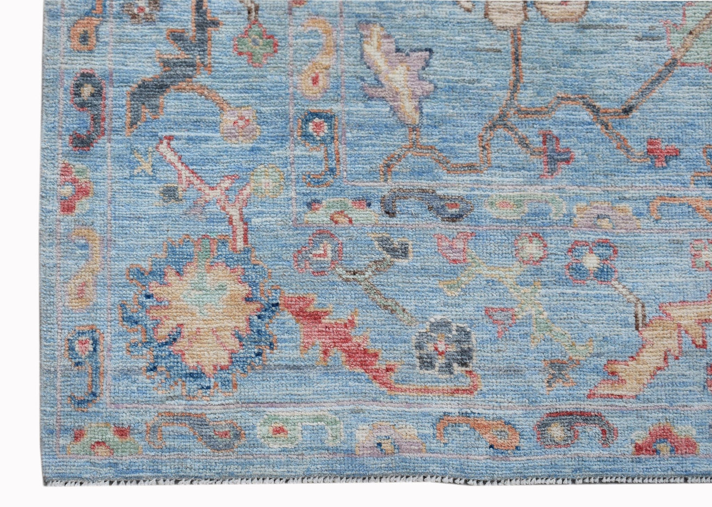 A handwoven transitional Oushak rug featuring a floral pattern in blue and multi-colored tones.