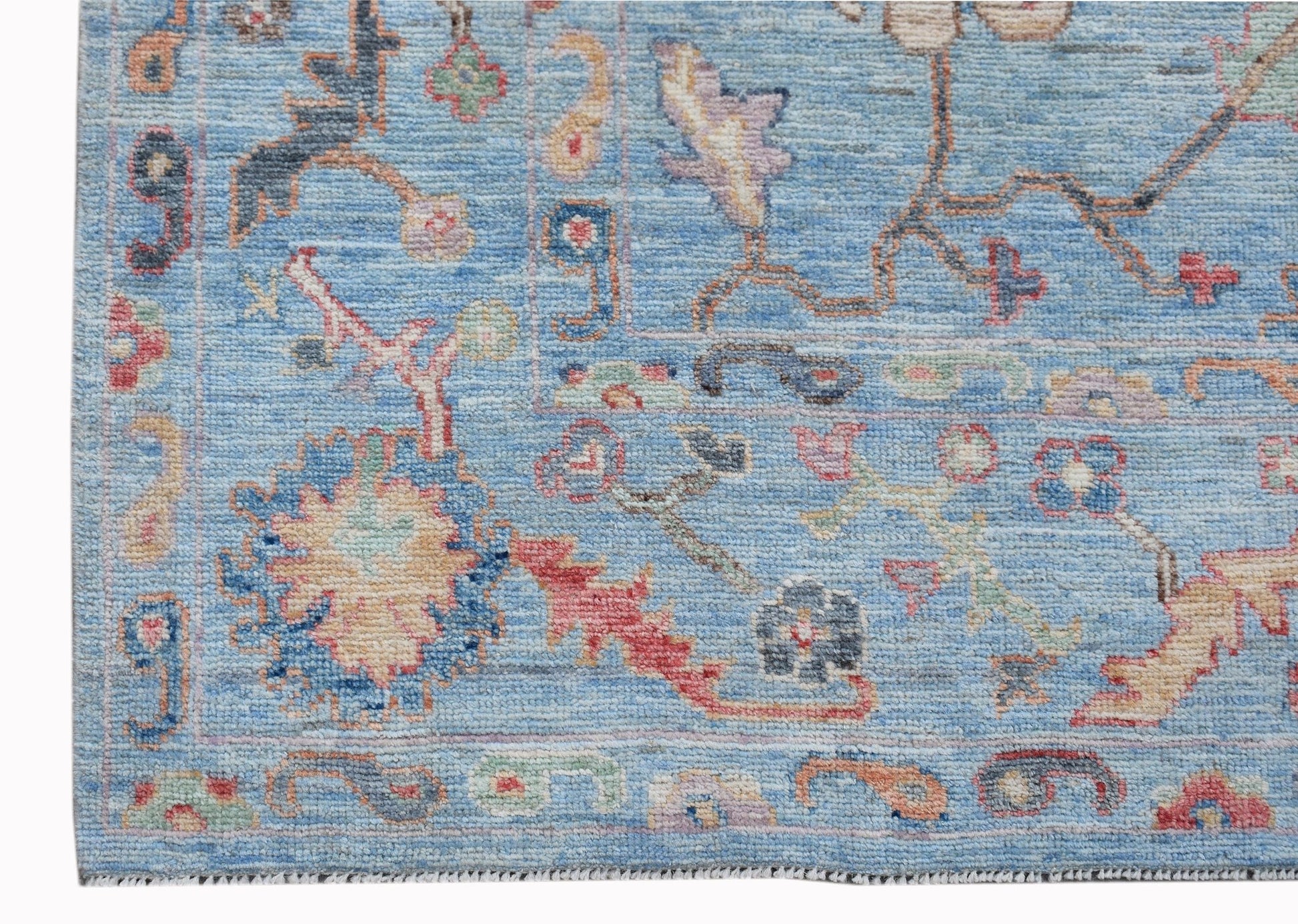 A handwoven transitional Oushak rug featuring a floral pattern in blue and multi-colored tones.