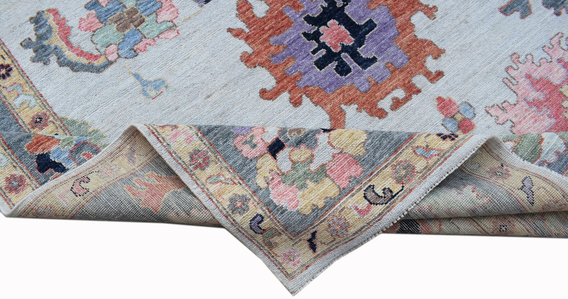 A handwoven transitional Oushak rug with a floral pattern in soft pastel and bold accent colors.