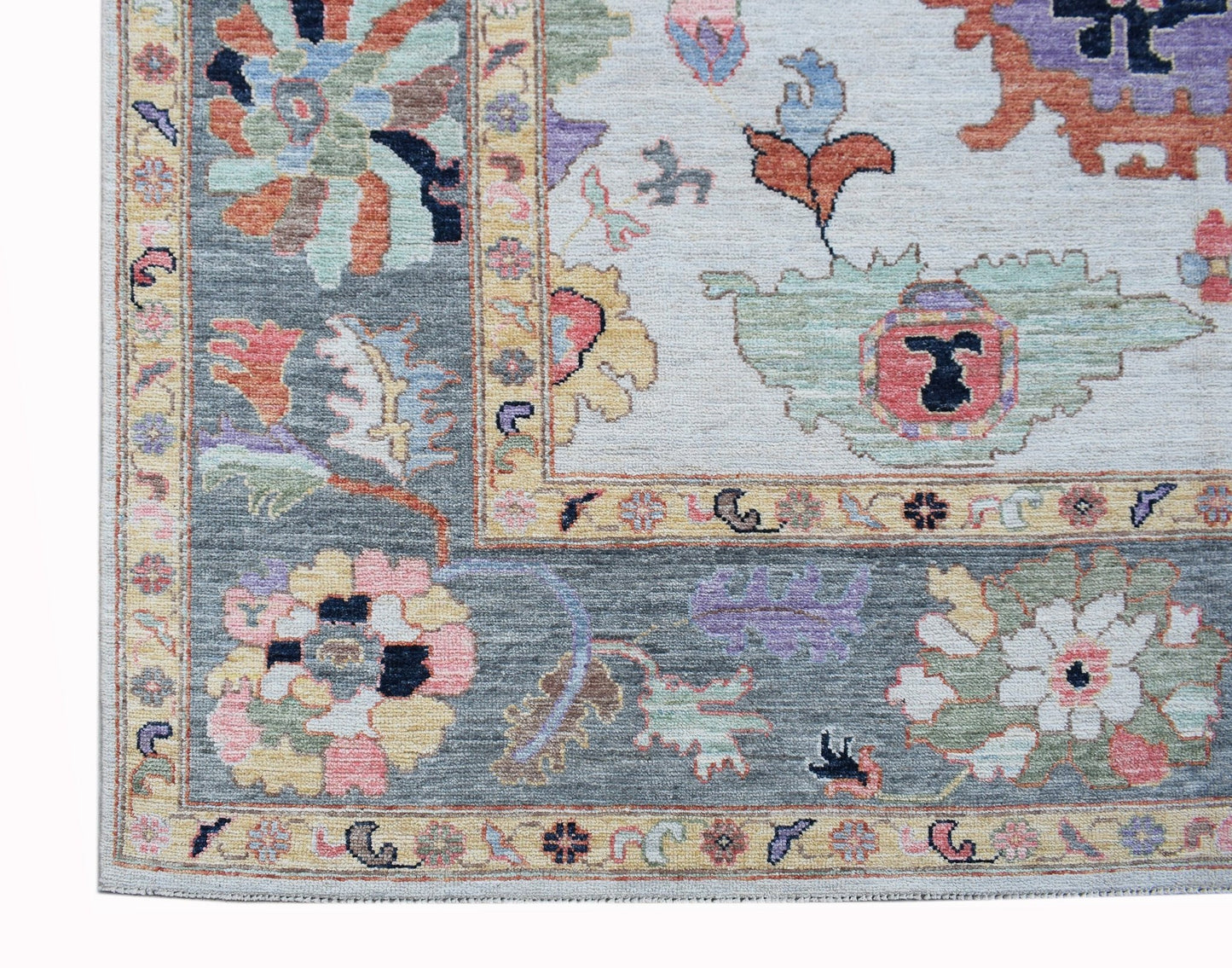 A transitional Oushak rug featuring a floral pattern in soft colors on a grey and cream background.