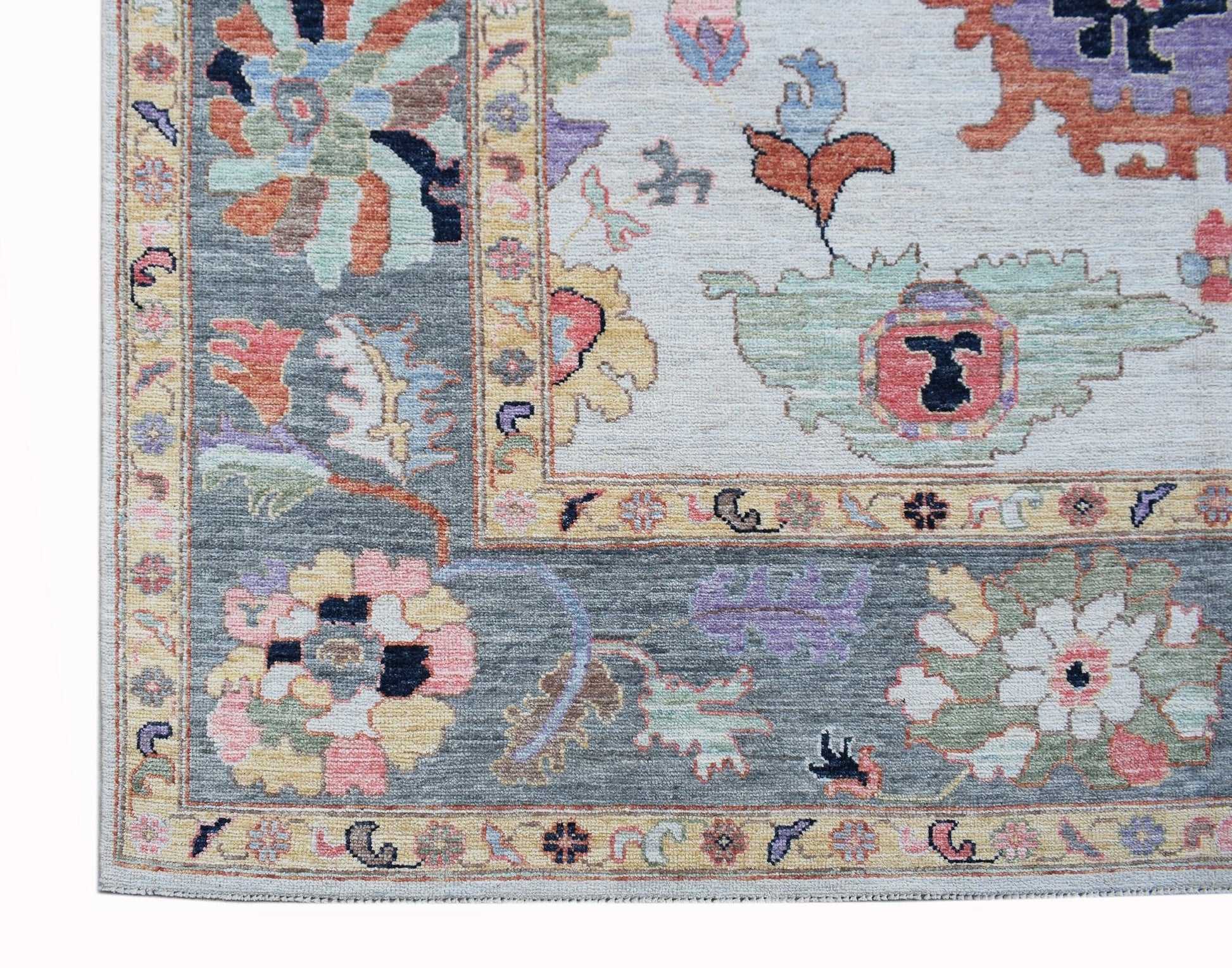 A transitional Oushak rug featuring a floral pattern in soft colors on a grey and cream background.