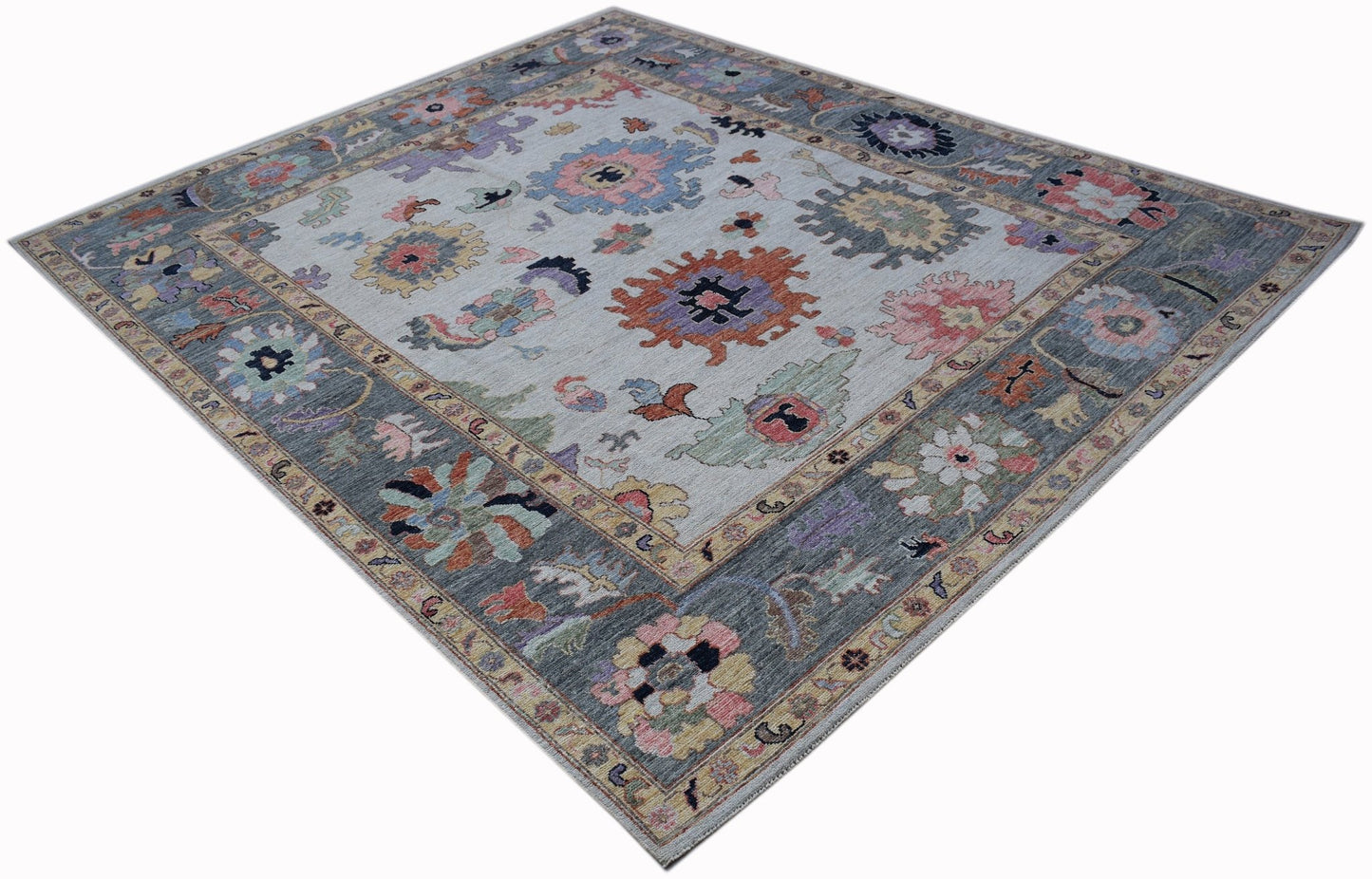 A handwoven transitional Oushak rug featuring a floral pattern in muted tones on a light background.