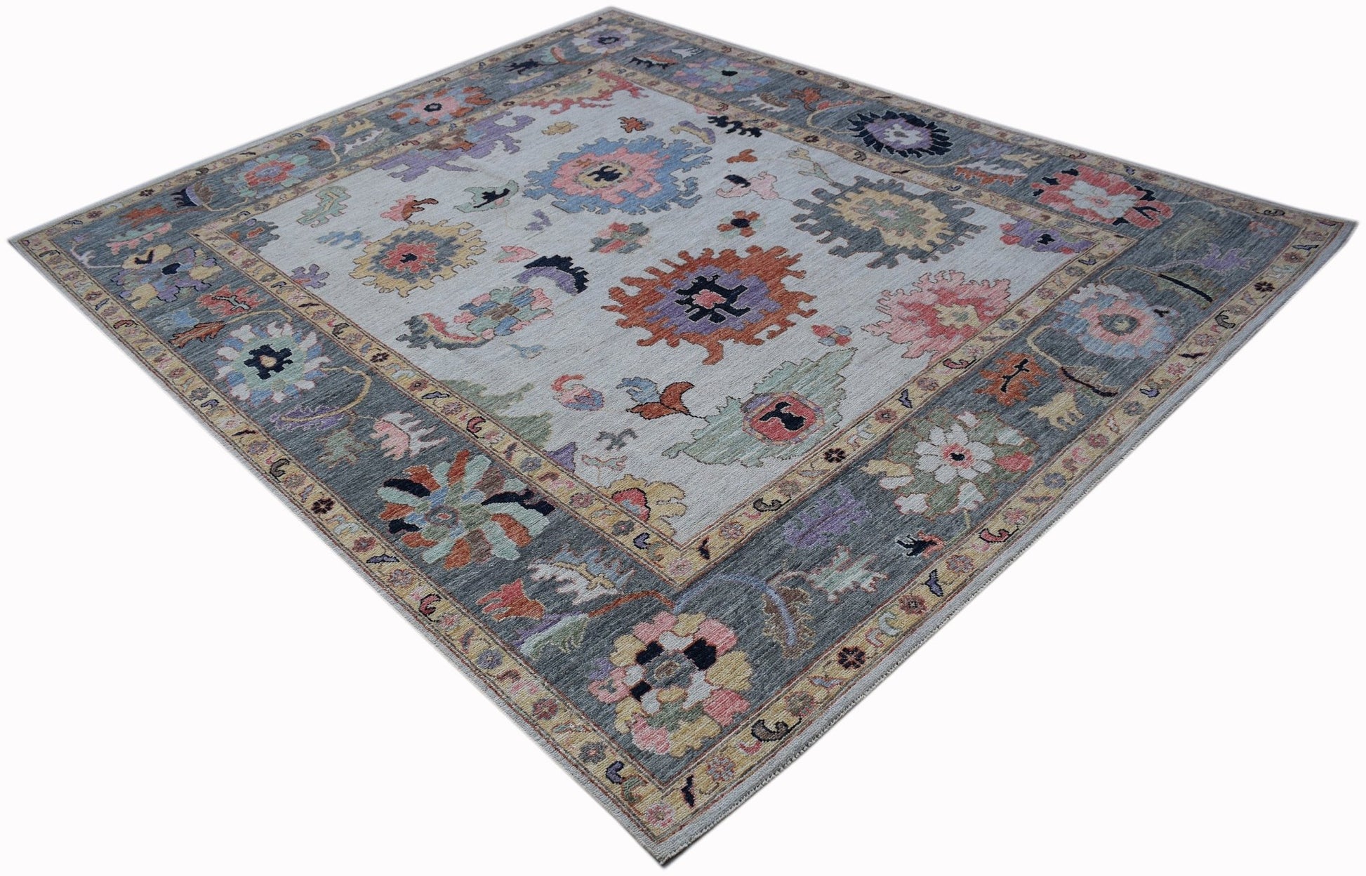 A handwoven transitional Oushak rug featuring a floral pattern in muted tones on a light background.