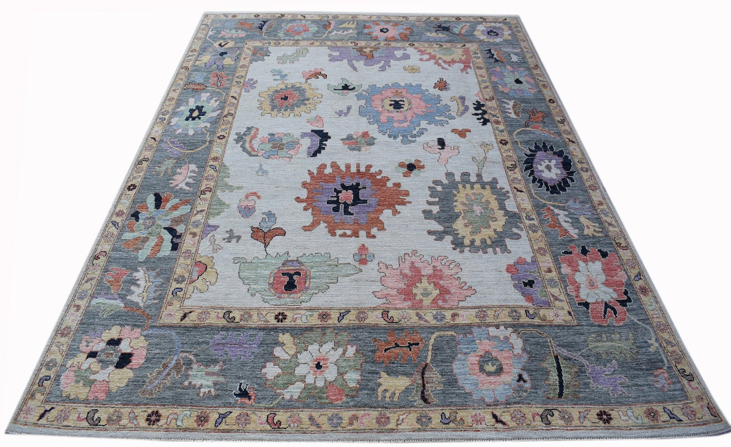 A handwoven transitional Oushak rug featuring a floral pattern in muted colors on a light field.
