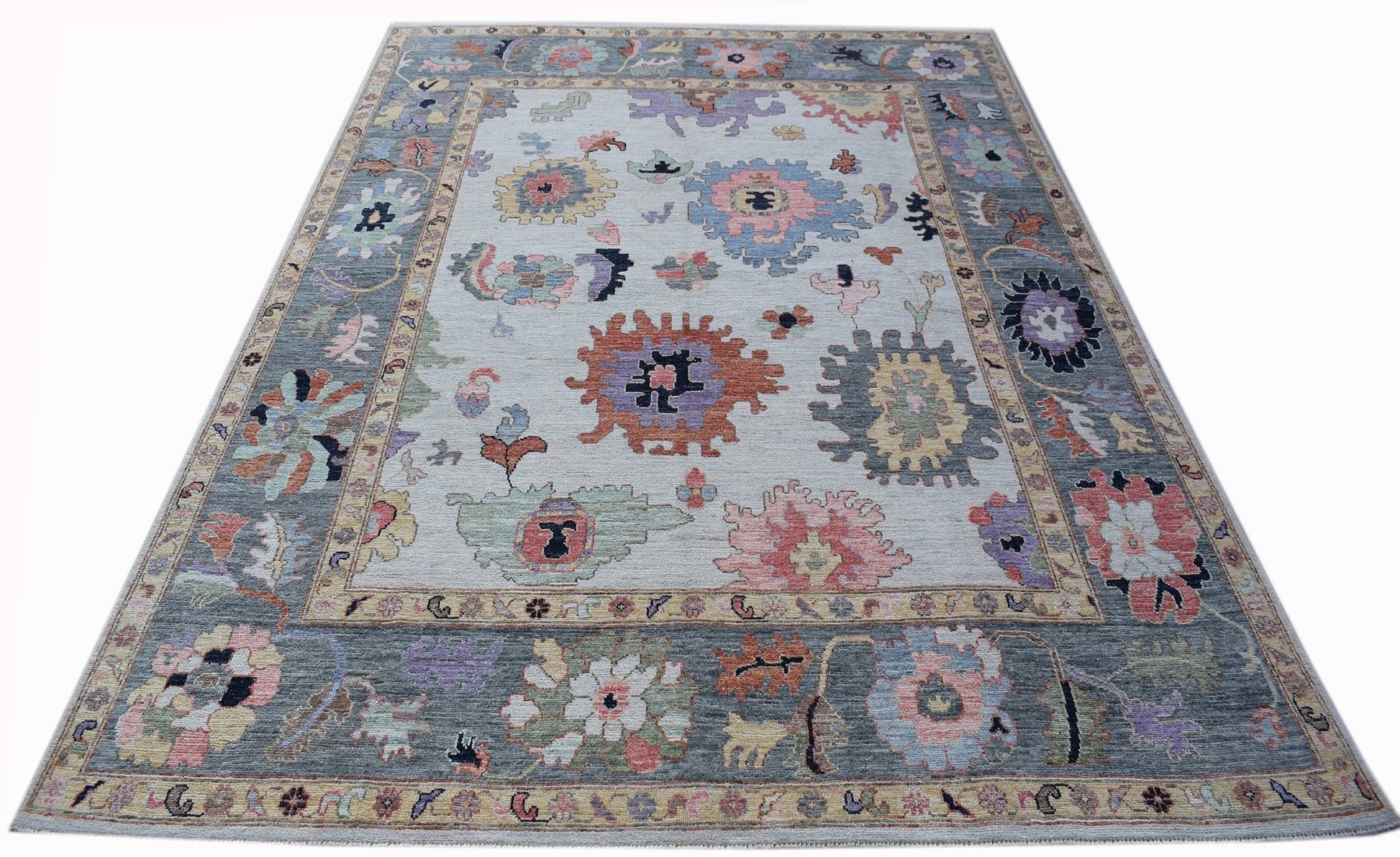 A handwoven transitional Oushak rug featuring a floral pattern in muted colors on a light field.