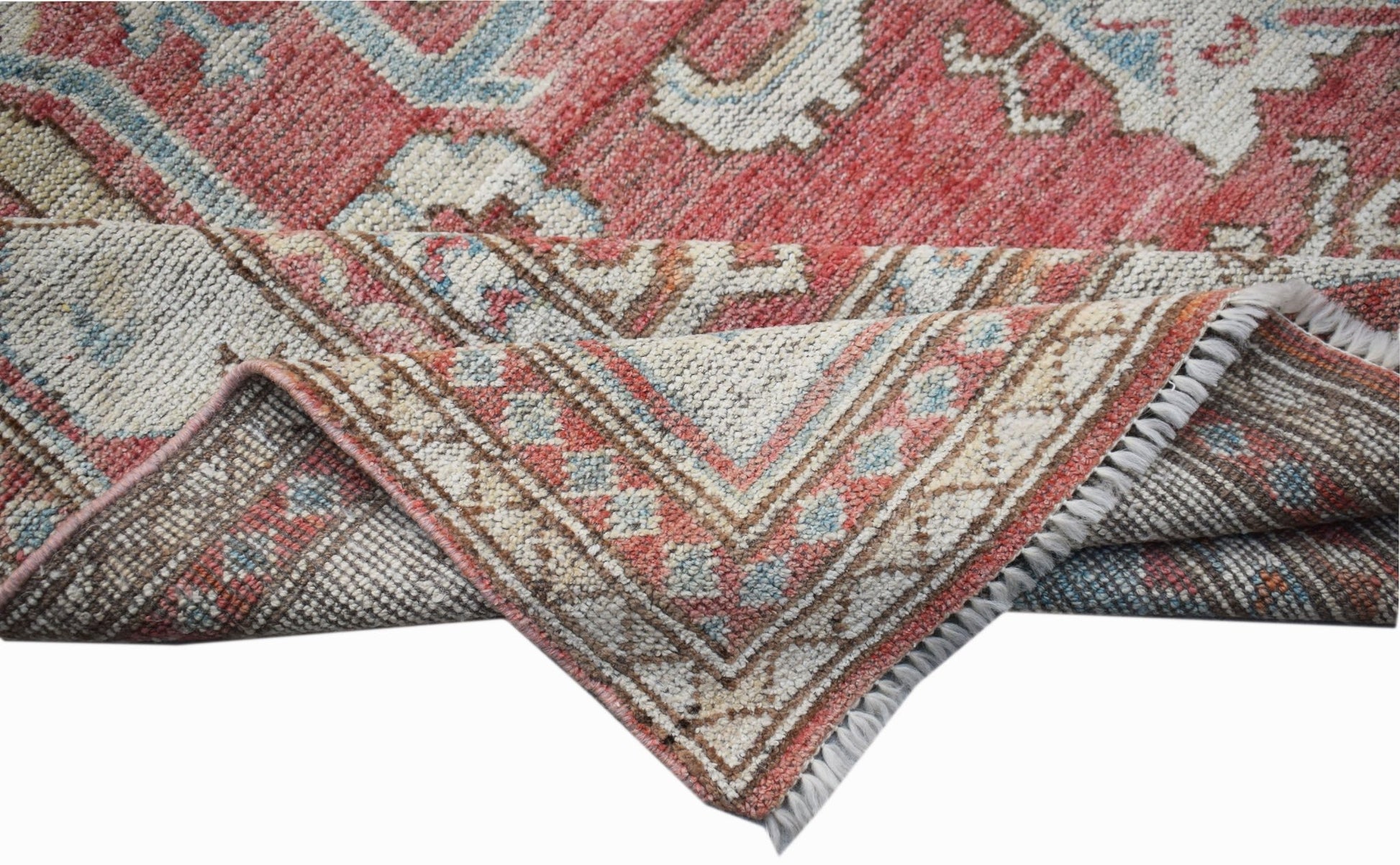 A handwoven transitional Oushak rug featuring a floral pattern in red, blue, and cream tones.