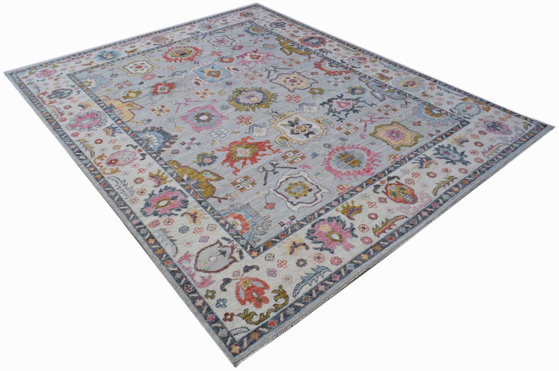 A handwoven transitional Oushak rug featuring a light grey field with colorful floral motifs.