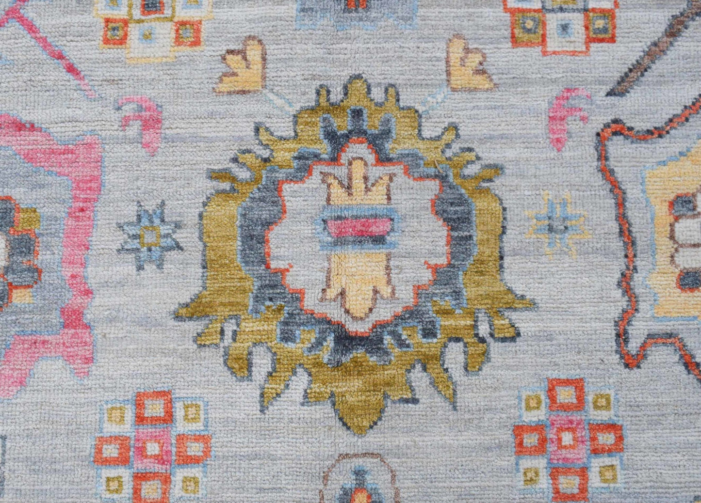 A handwoven transitional Oushak rug featuring a central floral medallion on a light grey field.