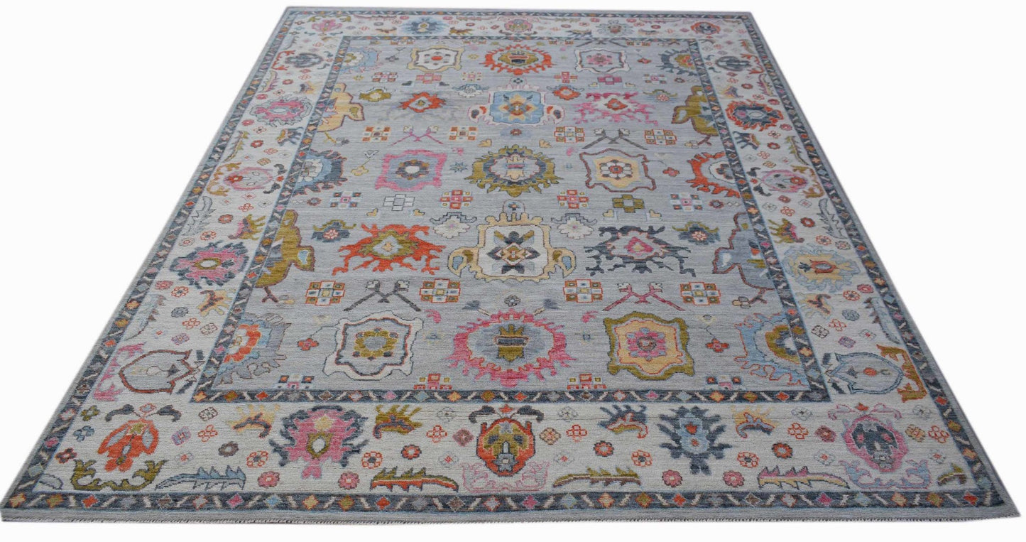 A handwoven transitional Oushak rug featuring a colorful floral pattern on a light grey background.