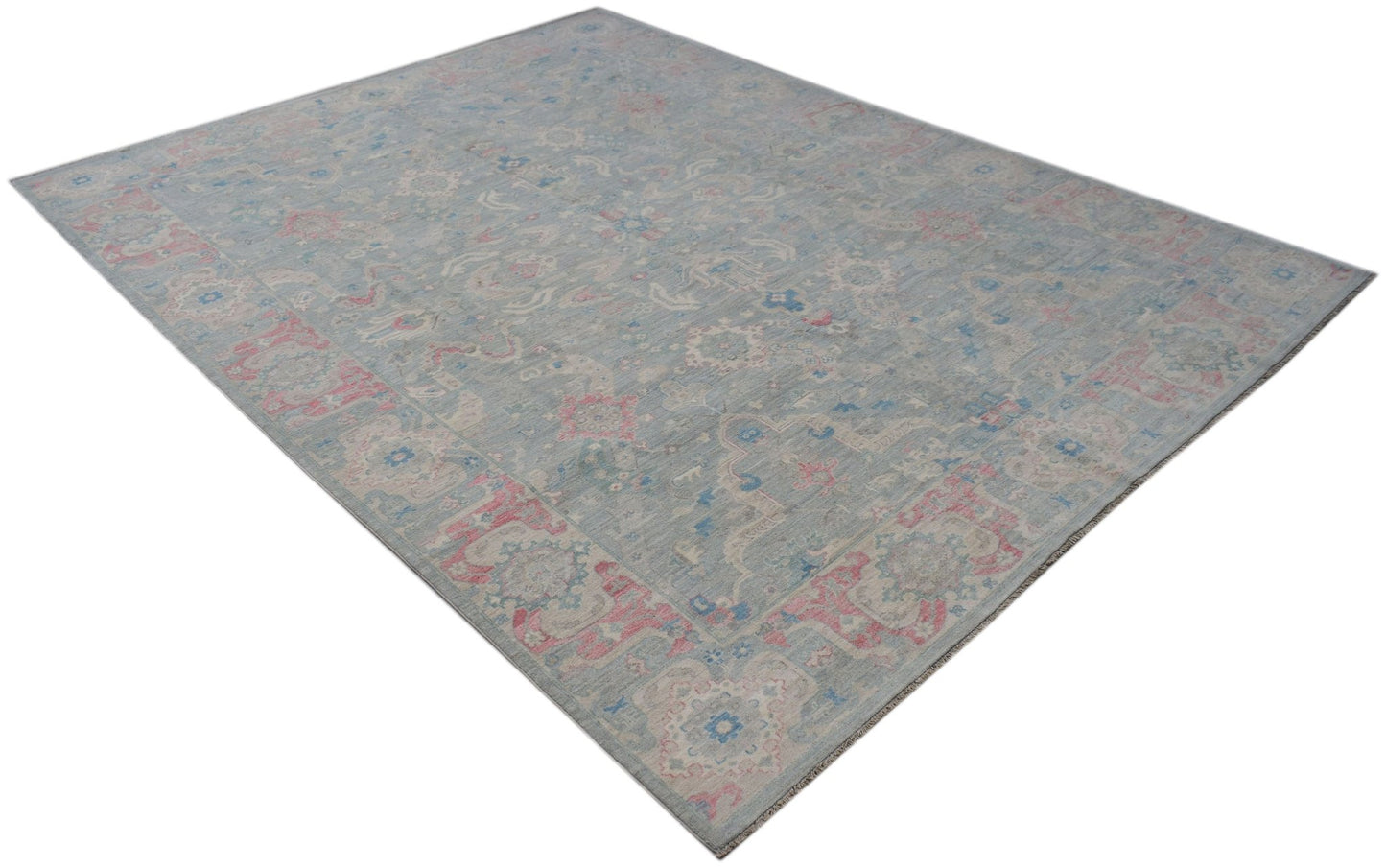 A handwoven transitional Oushak rug featuring a floral pattern in blue, pink, and cream tones.