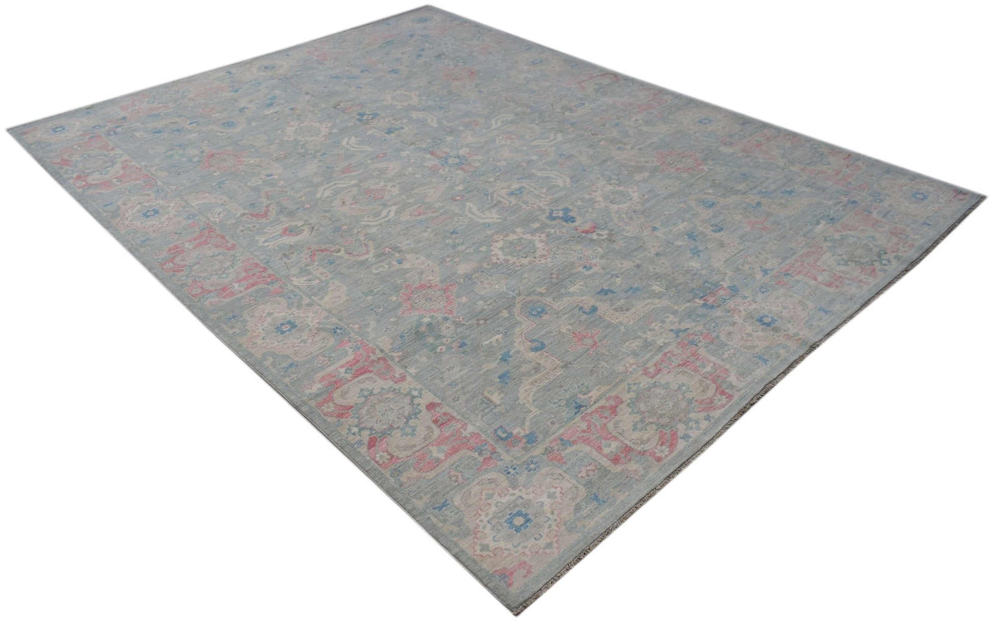 A handwoven transitional Oushak rug featuring a floral pattern in blue, pink, and cream tones.