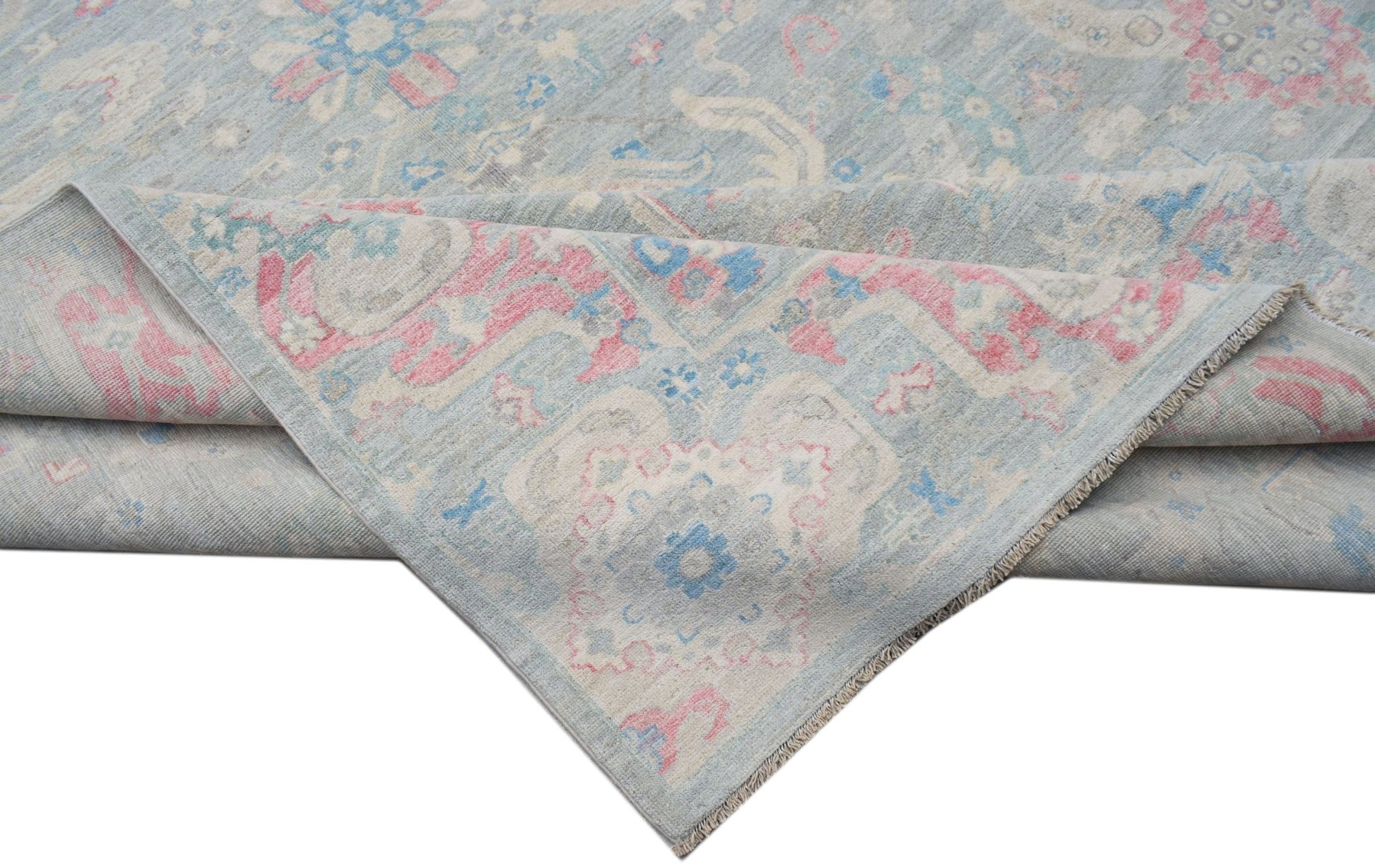 A handwoven transitional Oushak rug featuring a floral pattern in soft blue, pink, and cream tones.
