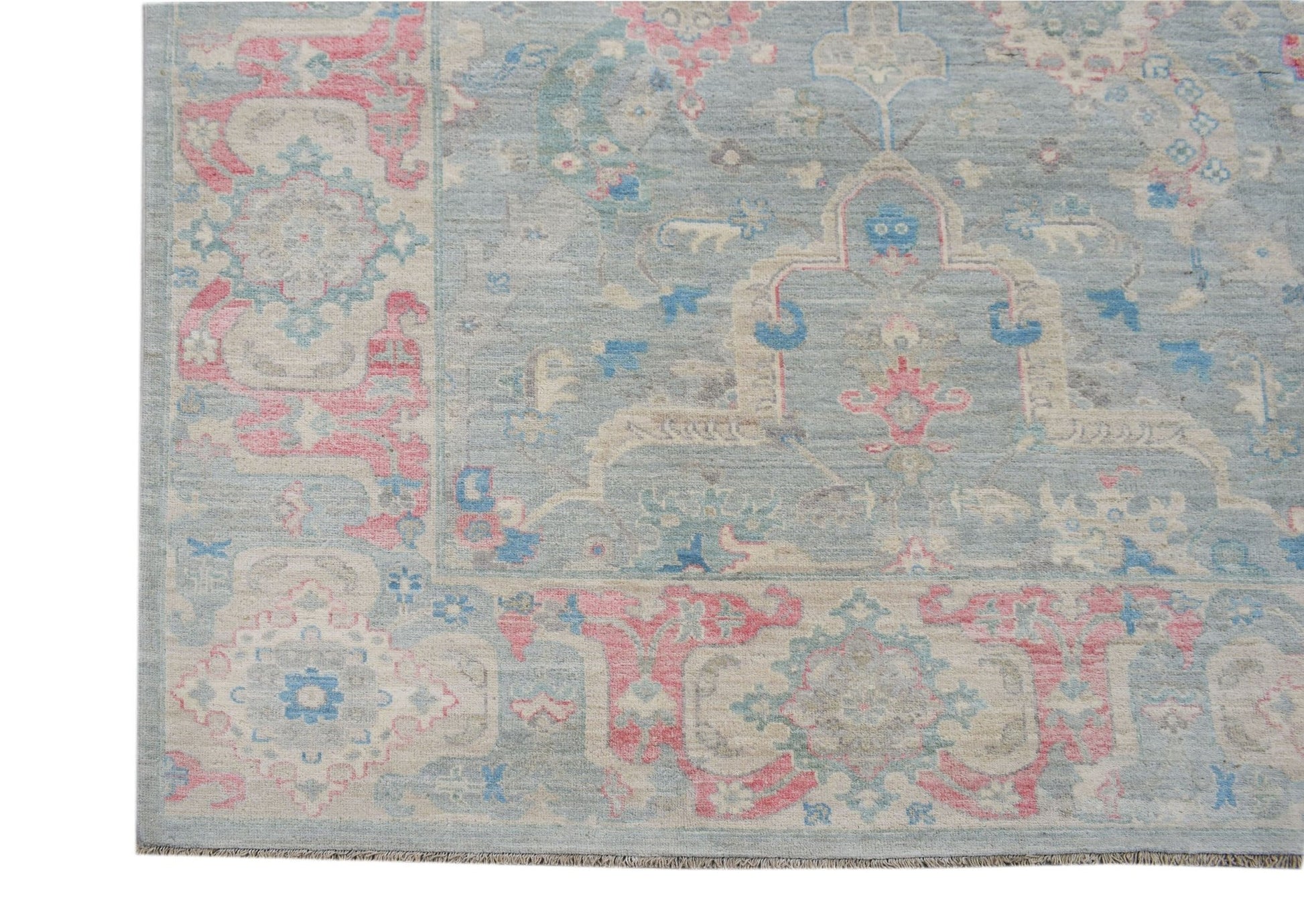 A handwoven transitional Oushak rug featuring a floral pattern in blue, pink, and cream tones.