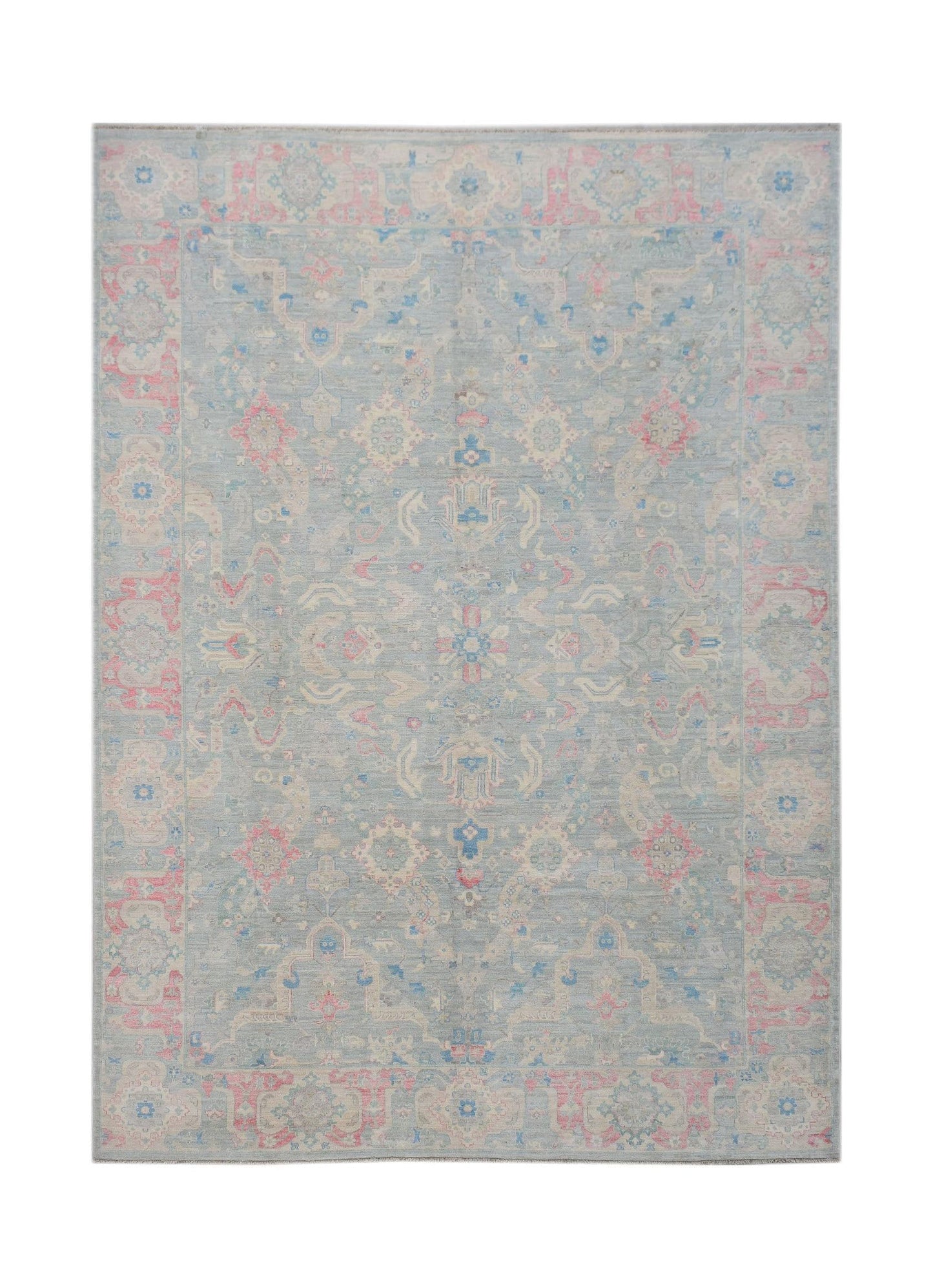 A handwoven transitional Oushak rug featuring a floral pattern in soft blue and pink tones.