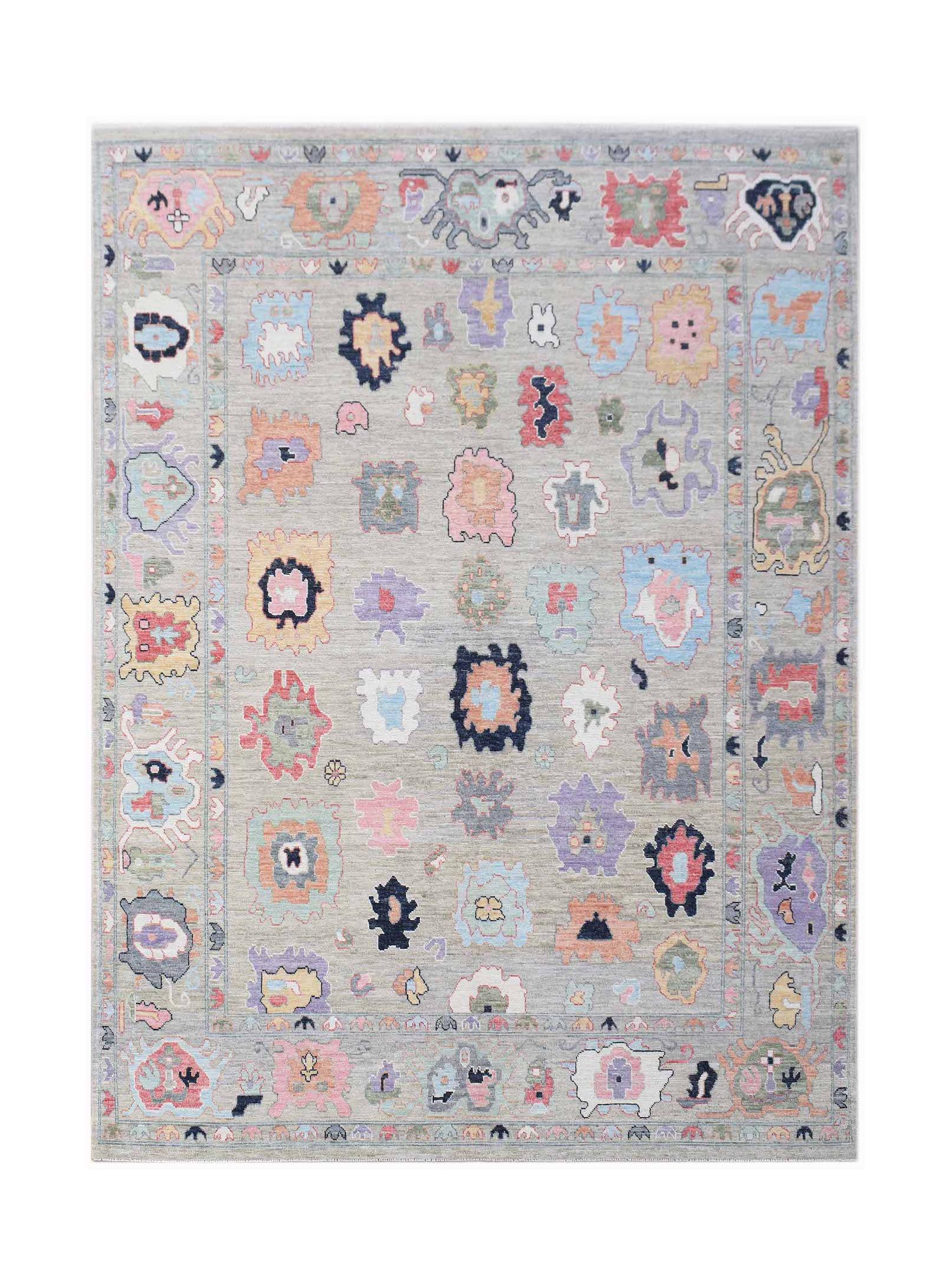 A handwoven transitional Oushak rug featuring colorful abstract motifs on a light gray background.