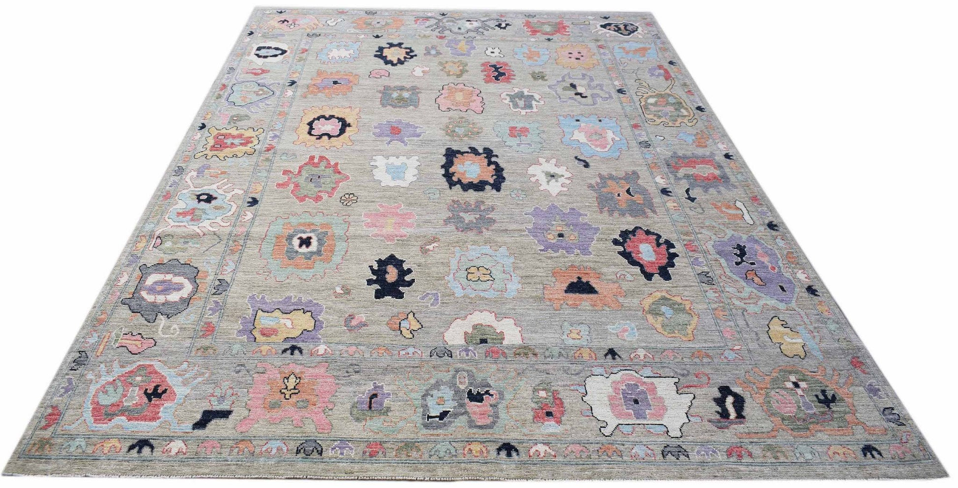 A handwoven transitional Oushak rug featuring a grey field with colorful floral motifs.
