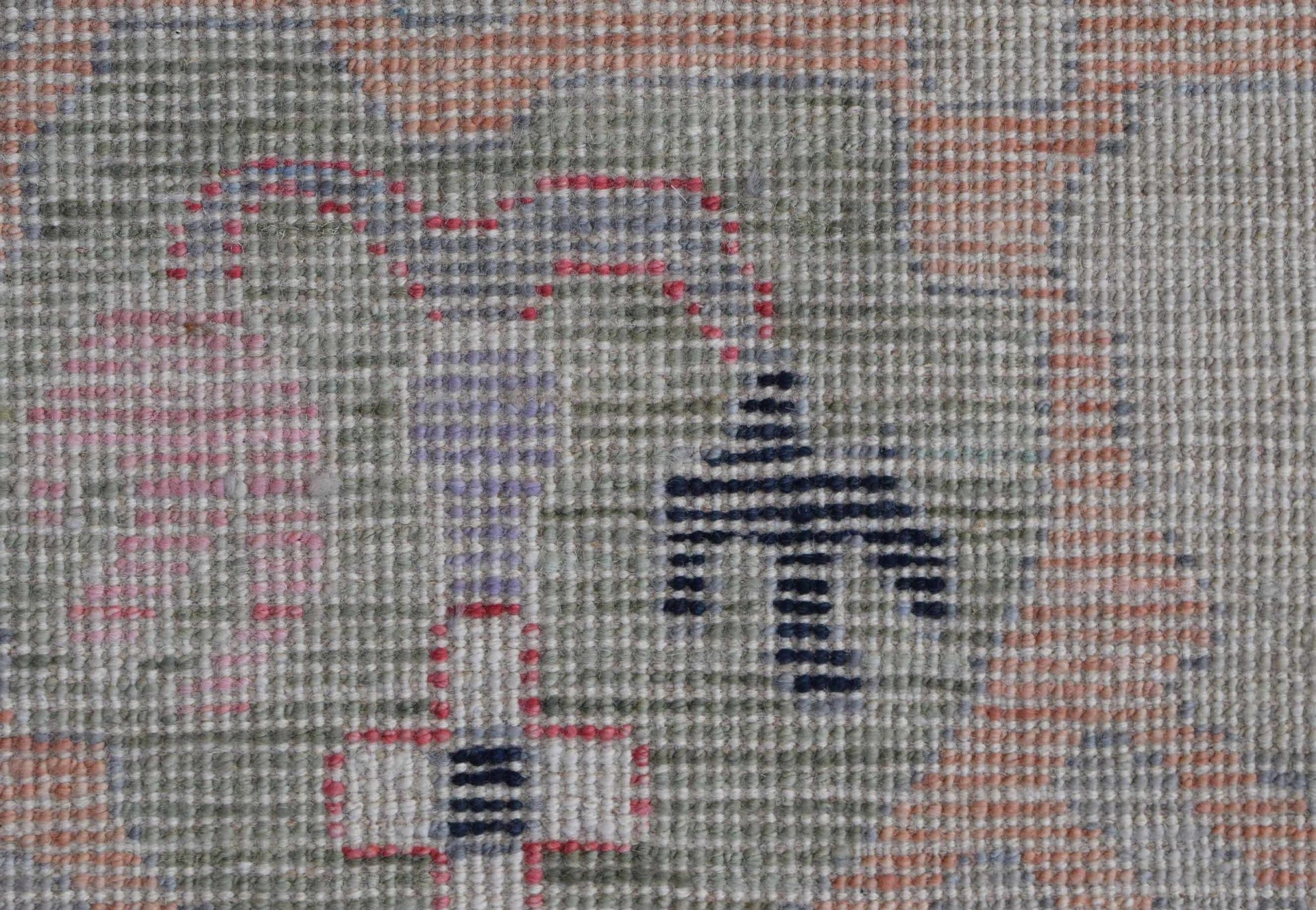 A close-up of a handwoven Oushak rug featuring a soft, muted pattern with geometric motifs.
