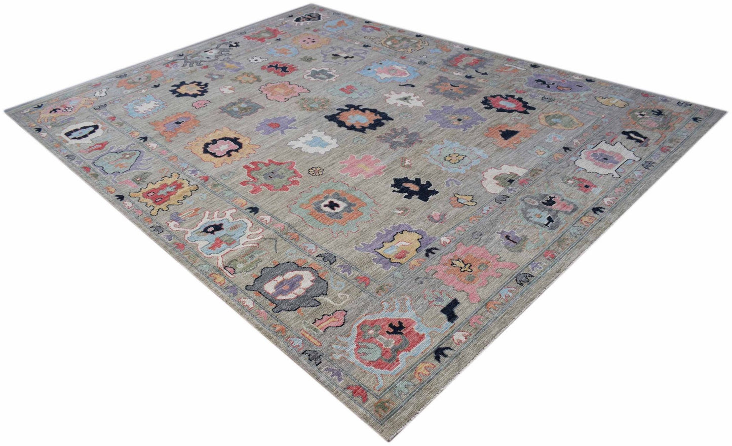 A handwoven transitional Oushak rug featuring a colorful floral pattern on a grey wool background.