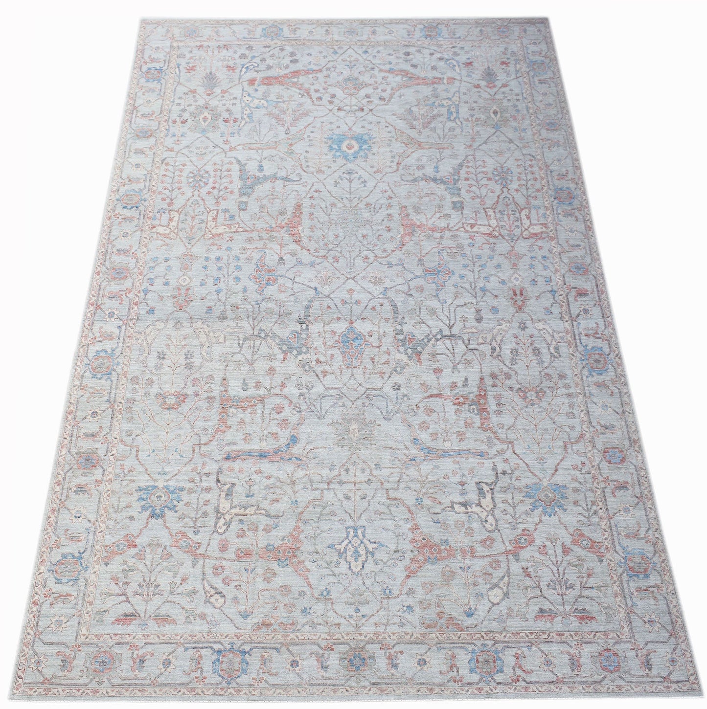 A handwoven transitional Oushak rug featuring a light blue field with floral patterns in soft tones.