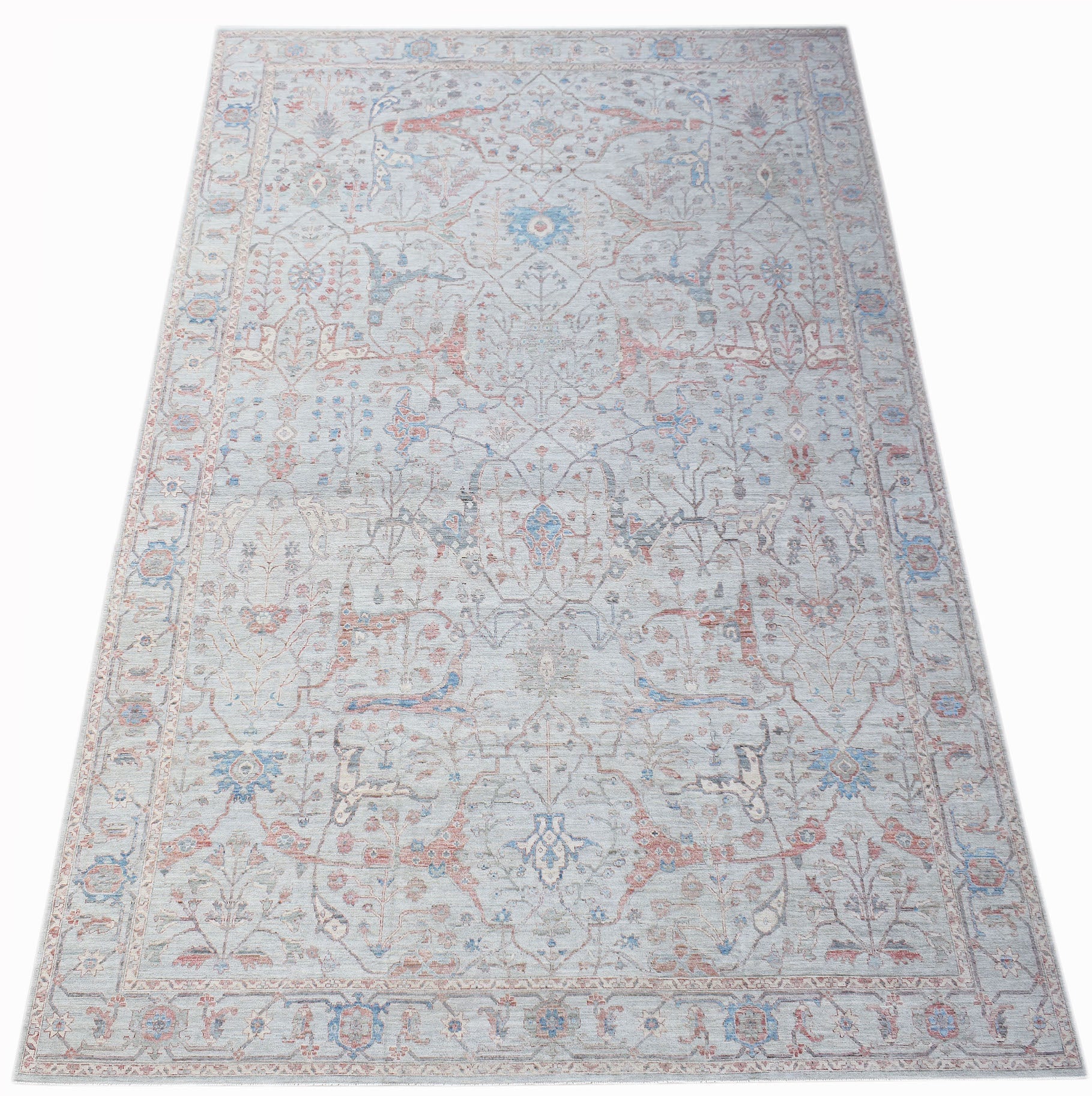 A handwoven transitional Oushak rug featuring a light blue field with floral patterns in soft tones.