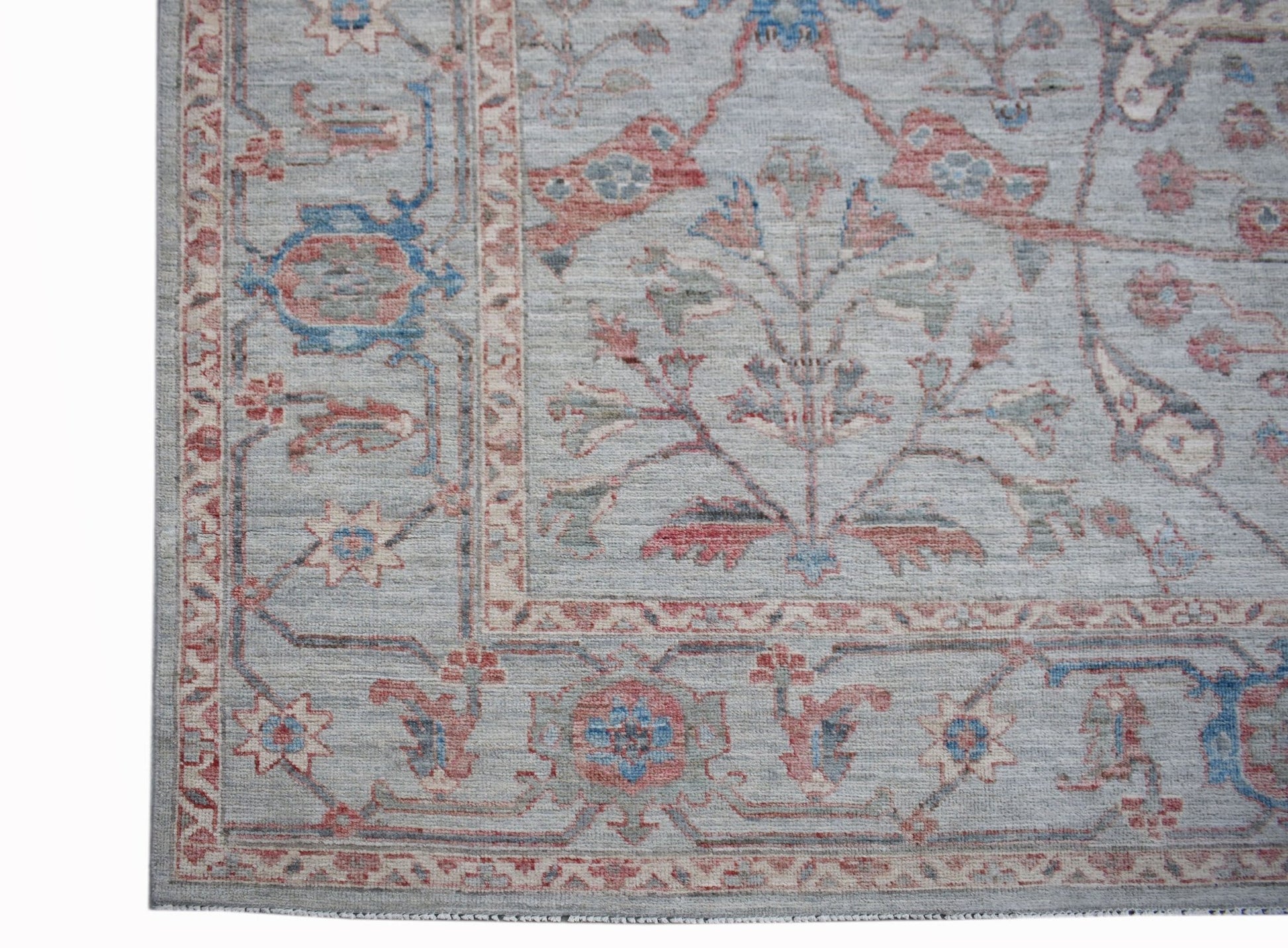 A handwoven transitional Oushak rug featuring a floral pattern in blue and red on a grey field.