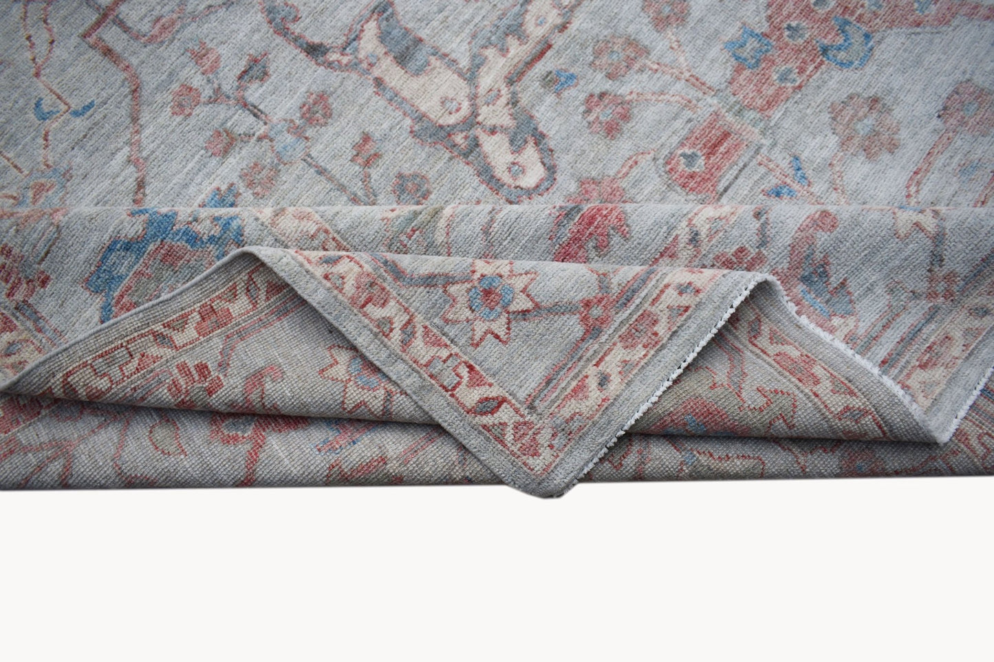 A handwoven transitional Oushak rug featuring a floral pattern in soft blue and red tones.