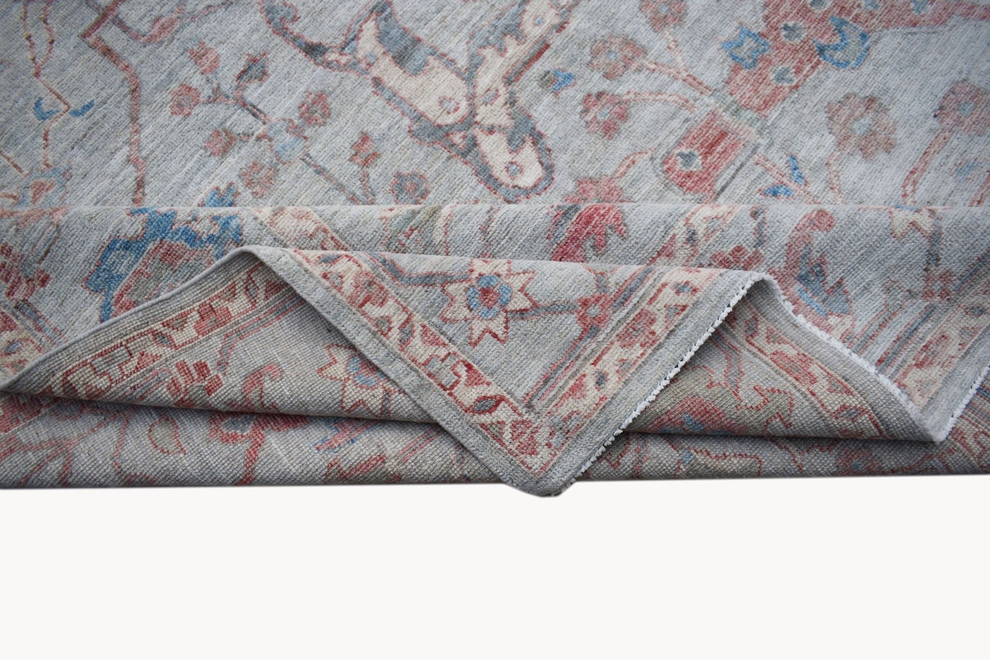 A handwoven transitional Oushak rug featuring a floral pattern in soft blue and red tones.