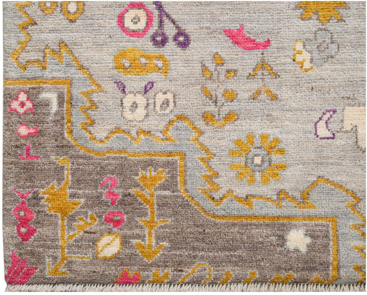 A hand-knotted wool rug featuring a transitional design with geometric motifs in grey and yellow.