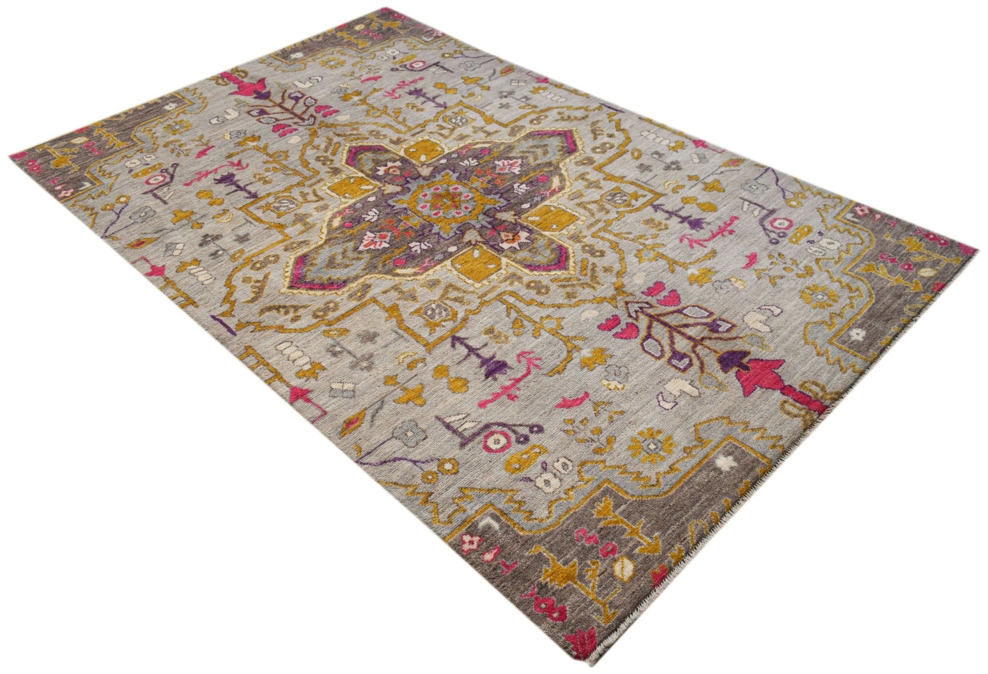 A hand-knotted wool rug featuring a grey background with geometric patterns in pink and gold.