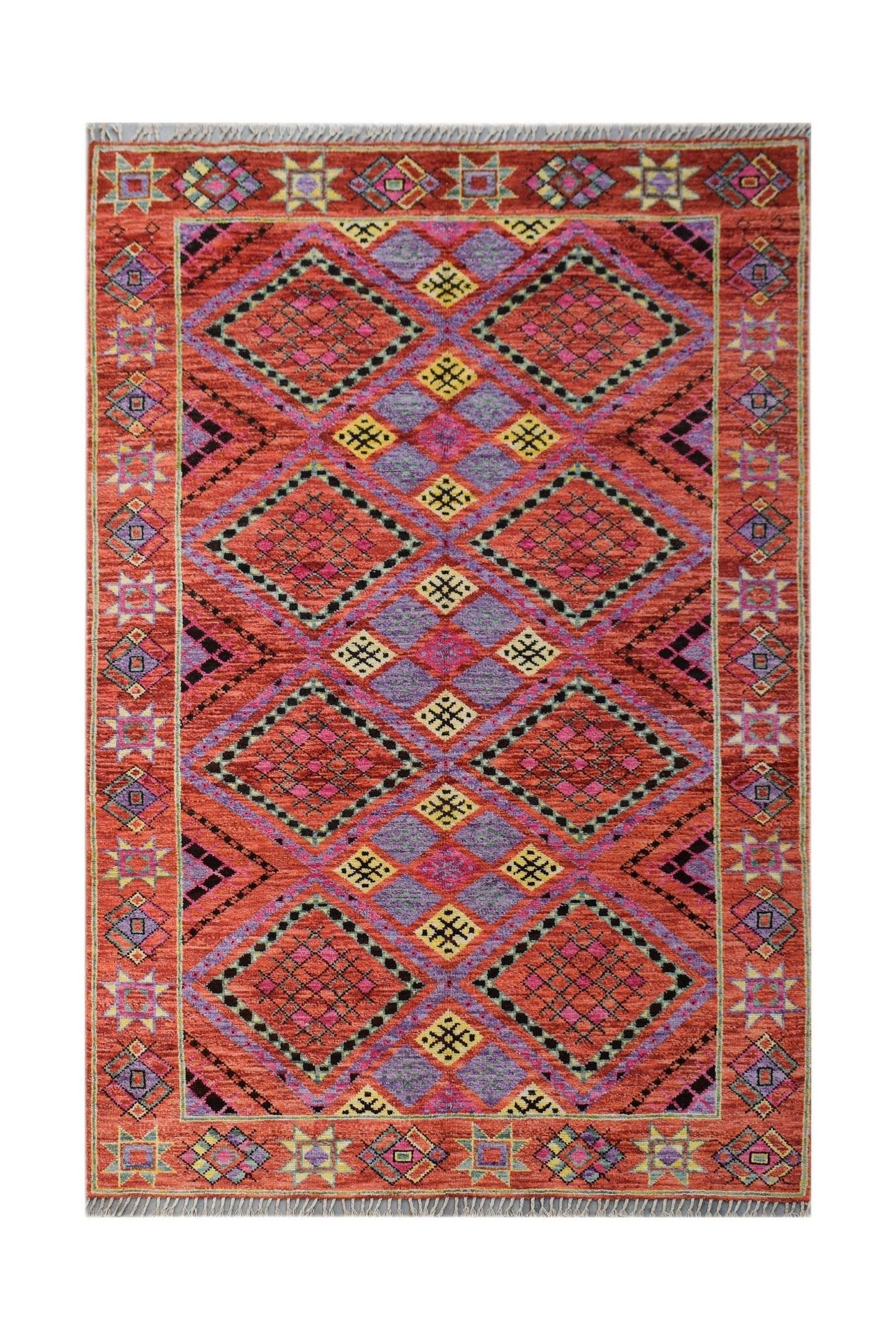 A hand-knotted wool rug featuring a vibrant geometric diamond pattern in red, purple, and yellow.