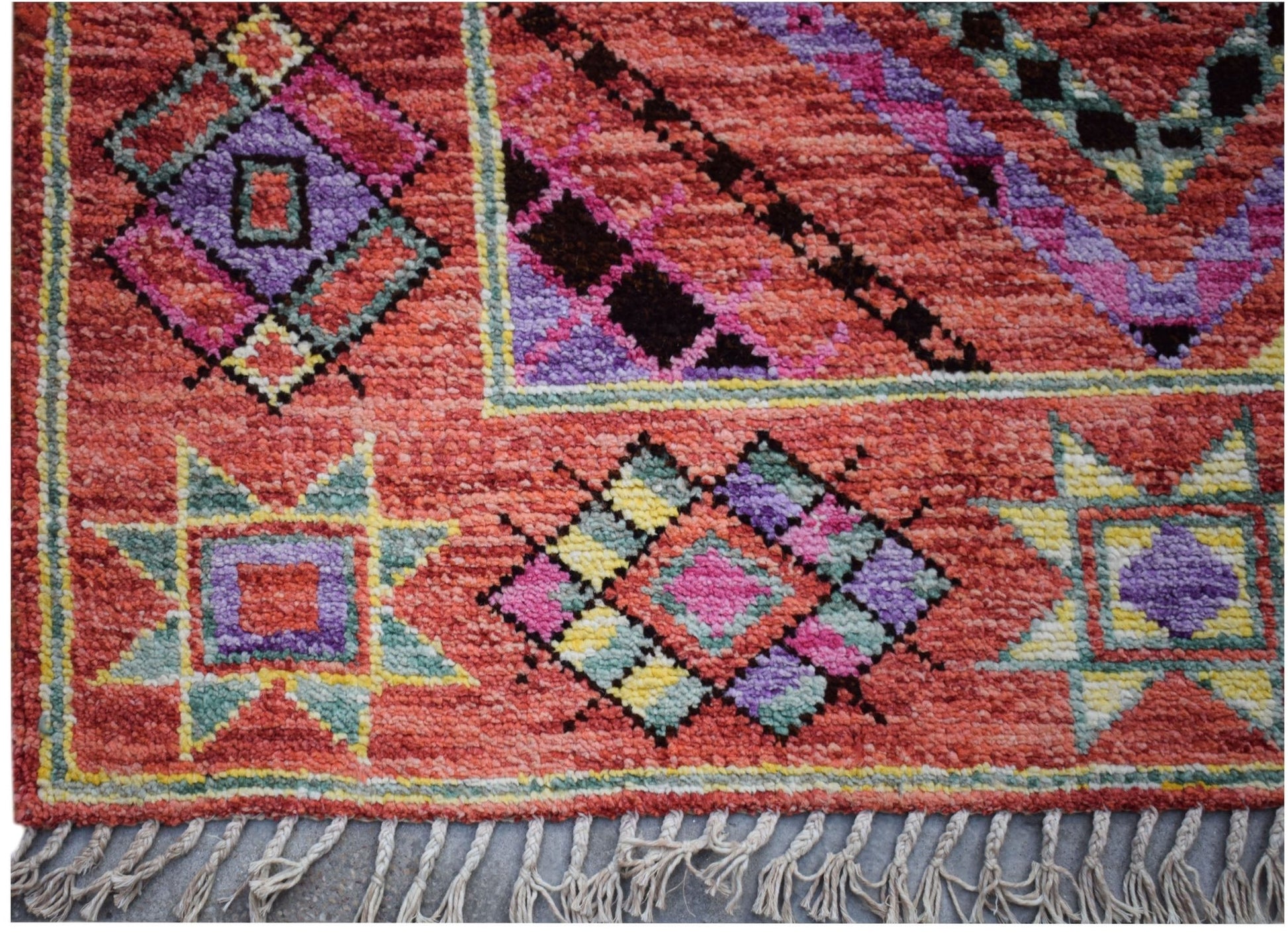 A hand-knotted wool rug featuring a vibrant red background with colorful geometric patterns.