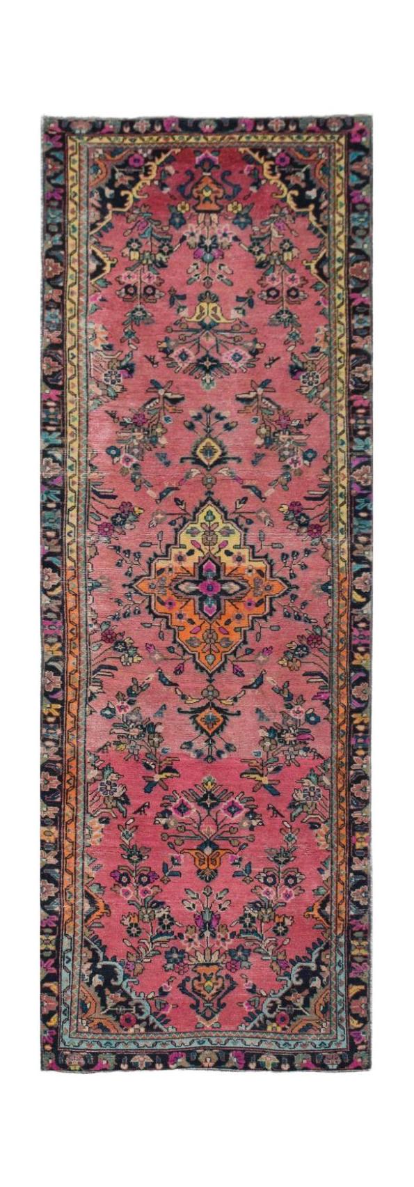 A vintage Persian runner rug featuring a vibrant pink field with floral motifs and a central medallion.