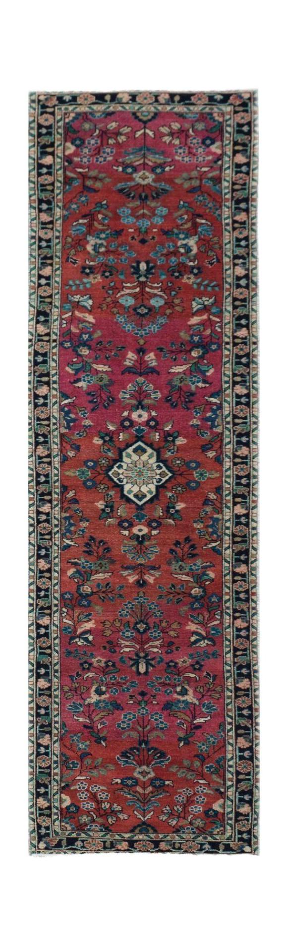 A vintage Persian runner rug featuring a floral pattern in shades of red, blue, and cream.