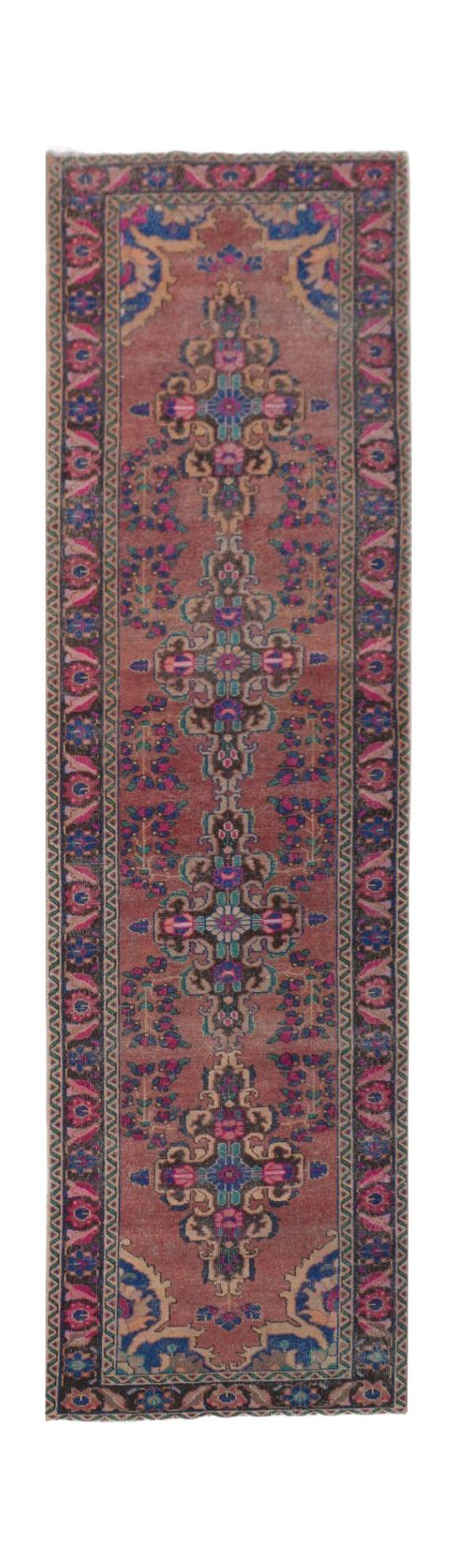 A vintage Persian runner rug featuring a central floral medallion pattern in muted red and blue.