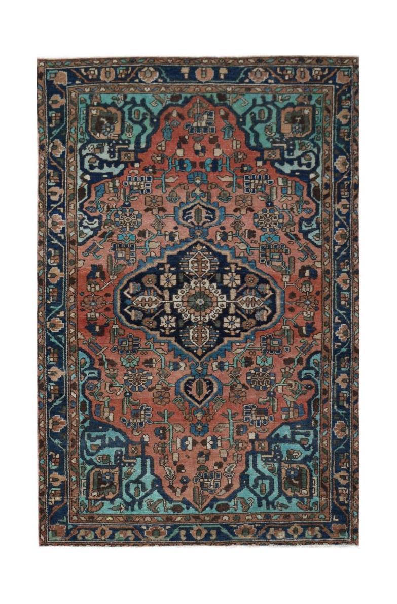 A vintage Persian wool rug featuring a central navy medallion on a salmon and teal floral field.