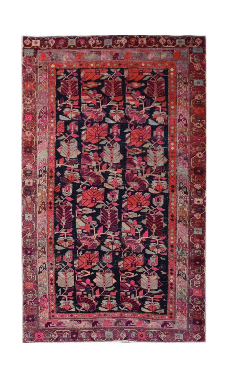 A vintage Persian rug featuring a dark field with repeating floral motifs and a patterned border.