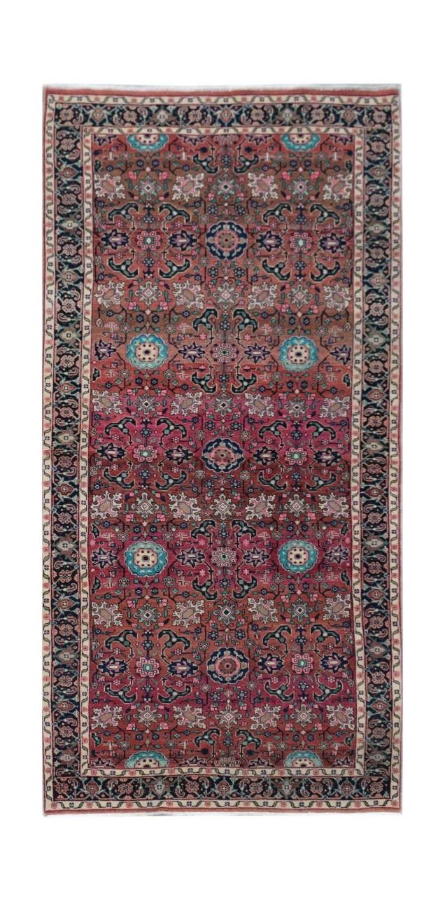 A rectangular vintage Persian rug featuring a floral pattern in shades of red, blue, and cream.