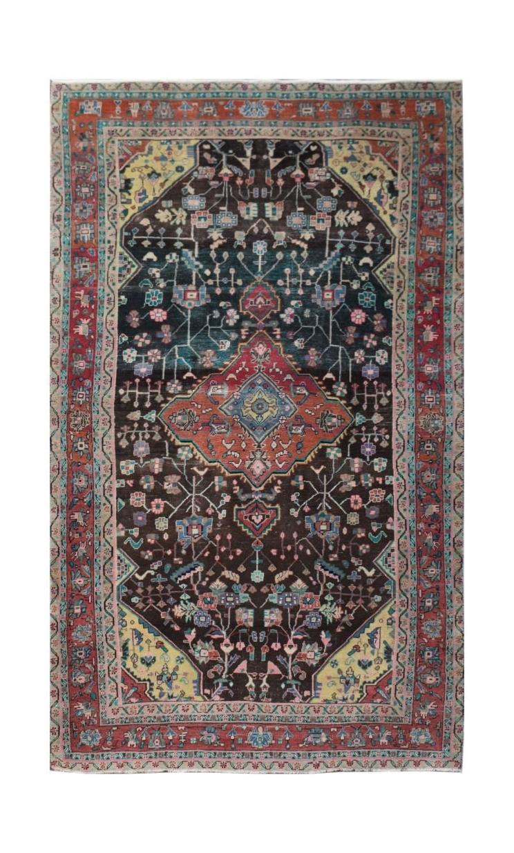 A rectangular vintage Persian rug featuring a dark central field with a geometric floral pattern.
