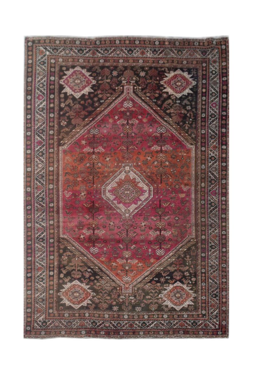 A handmade vintage Persian wool rug featuring a large central diamond medallion in red and orange.