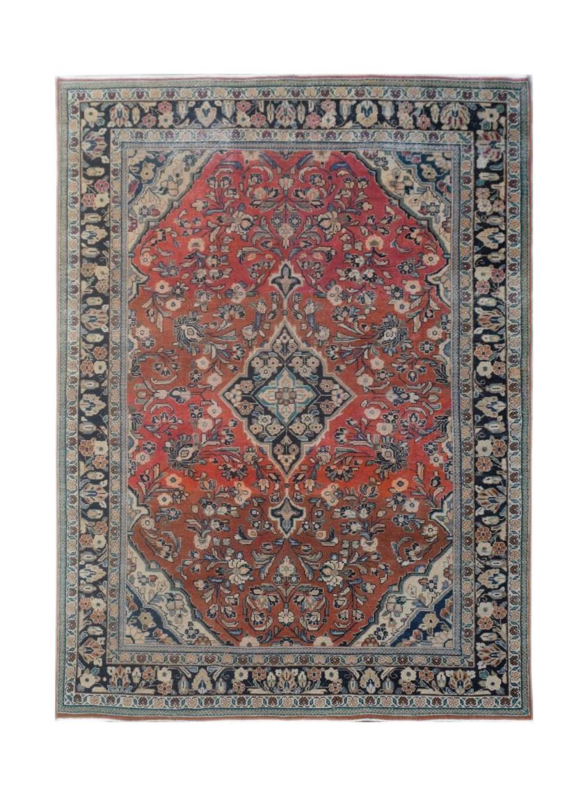 A vintage handmade Persian wool rug featuring a central medallion on a red floral field.